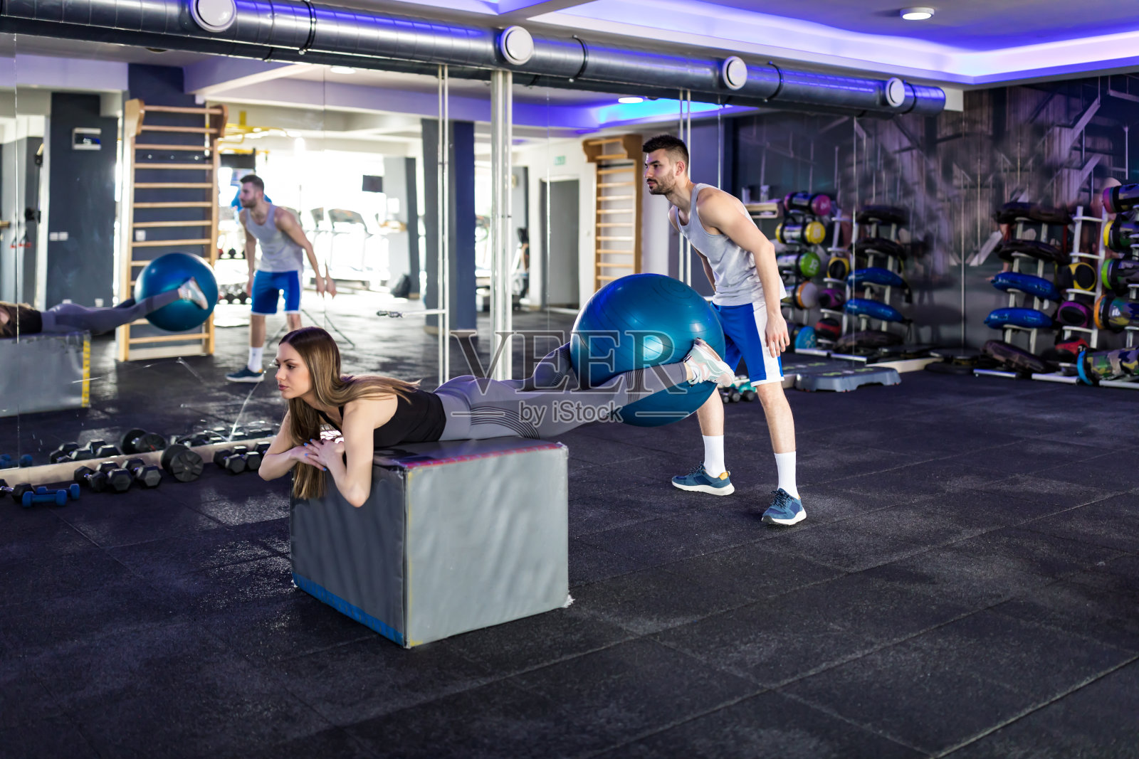 一名女子在教练的帮助下在健身房锻炼照片摄影图片