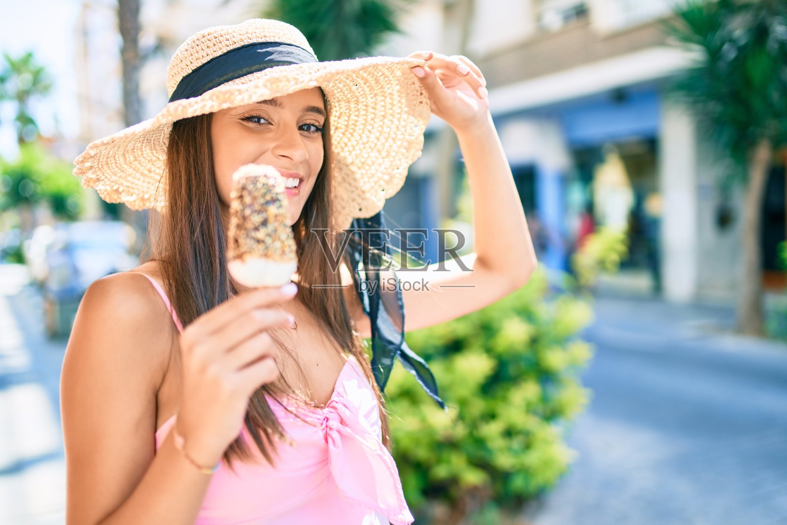 年轻的西班牙妇女在度假穿着夏天的风格吃冰淇淋在城市的街道照片摄影图片
