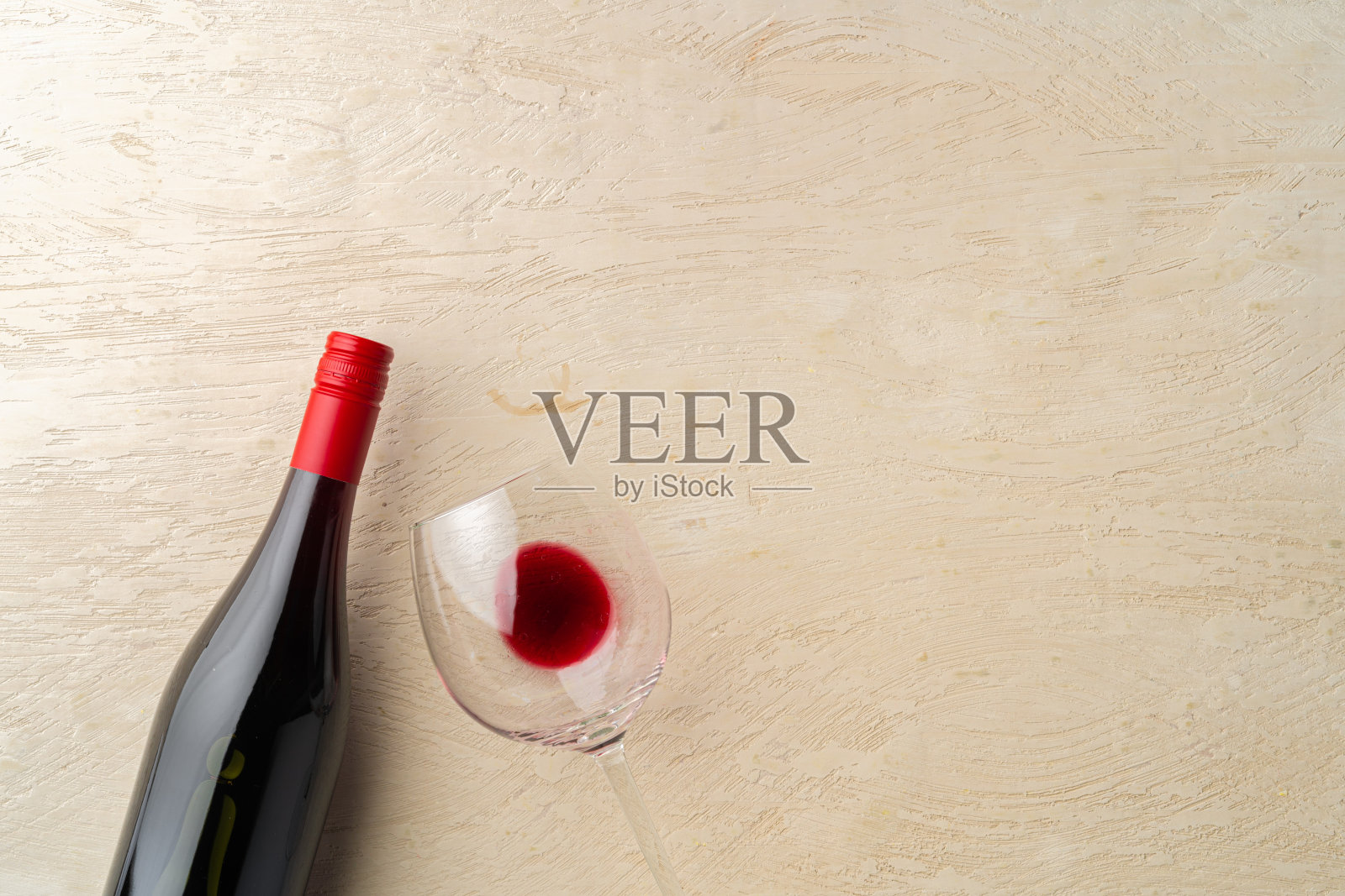 一瓶和一杯红酒平摊在灰色的背景上照片摄影图片