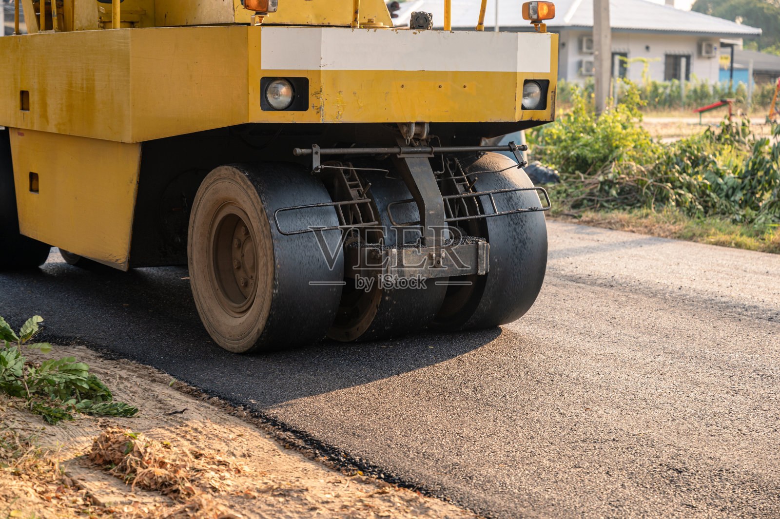 重型振动黄色压路机或土壤压实机在热拌沥青路面上工作照片摄影图片