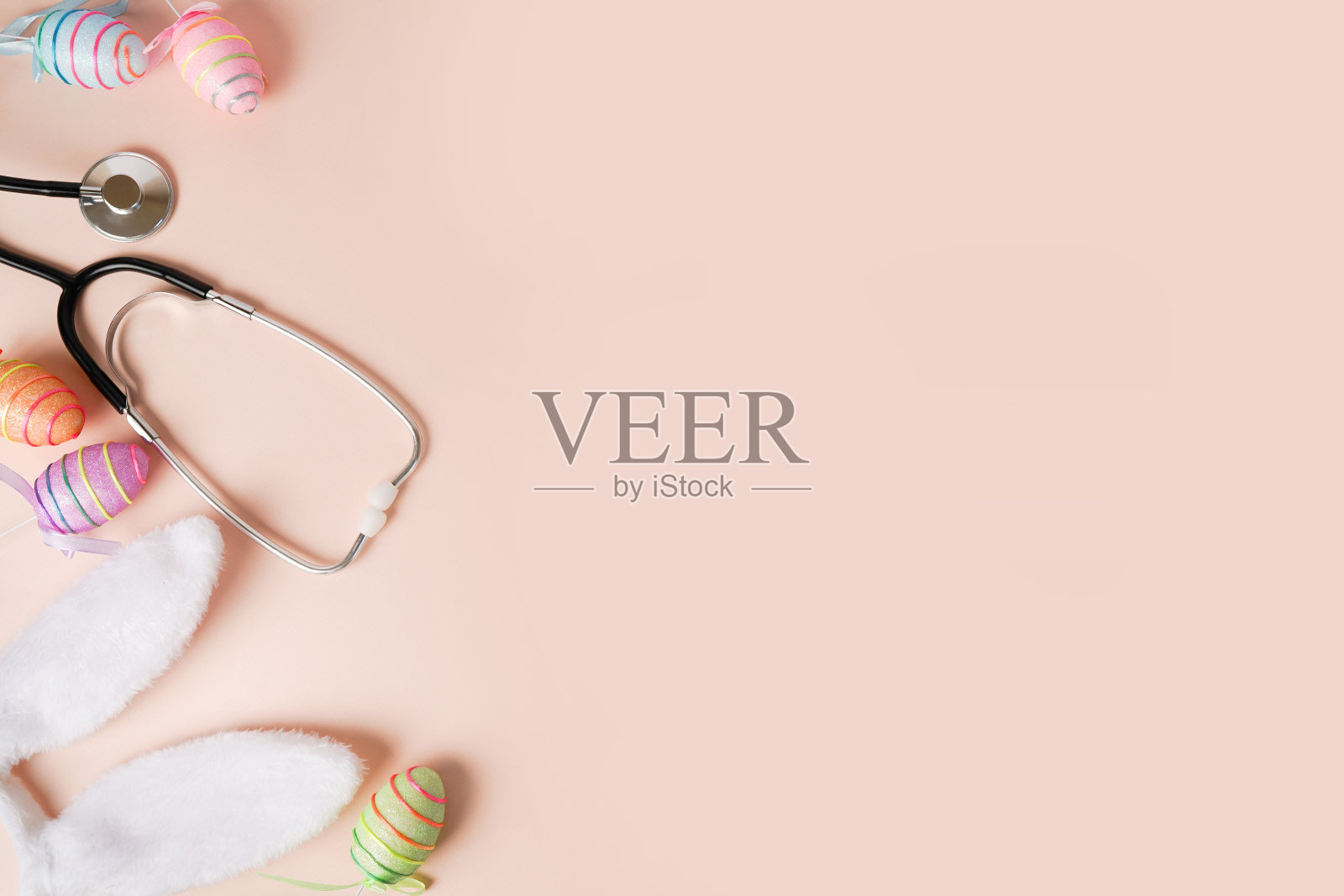 听诊器，复活节彩蛋，粉色背景的兔子耳朵，还有拷贝空间照片摄影图片