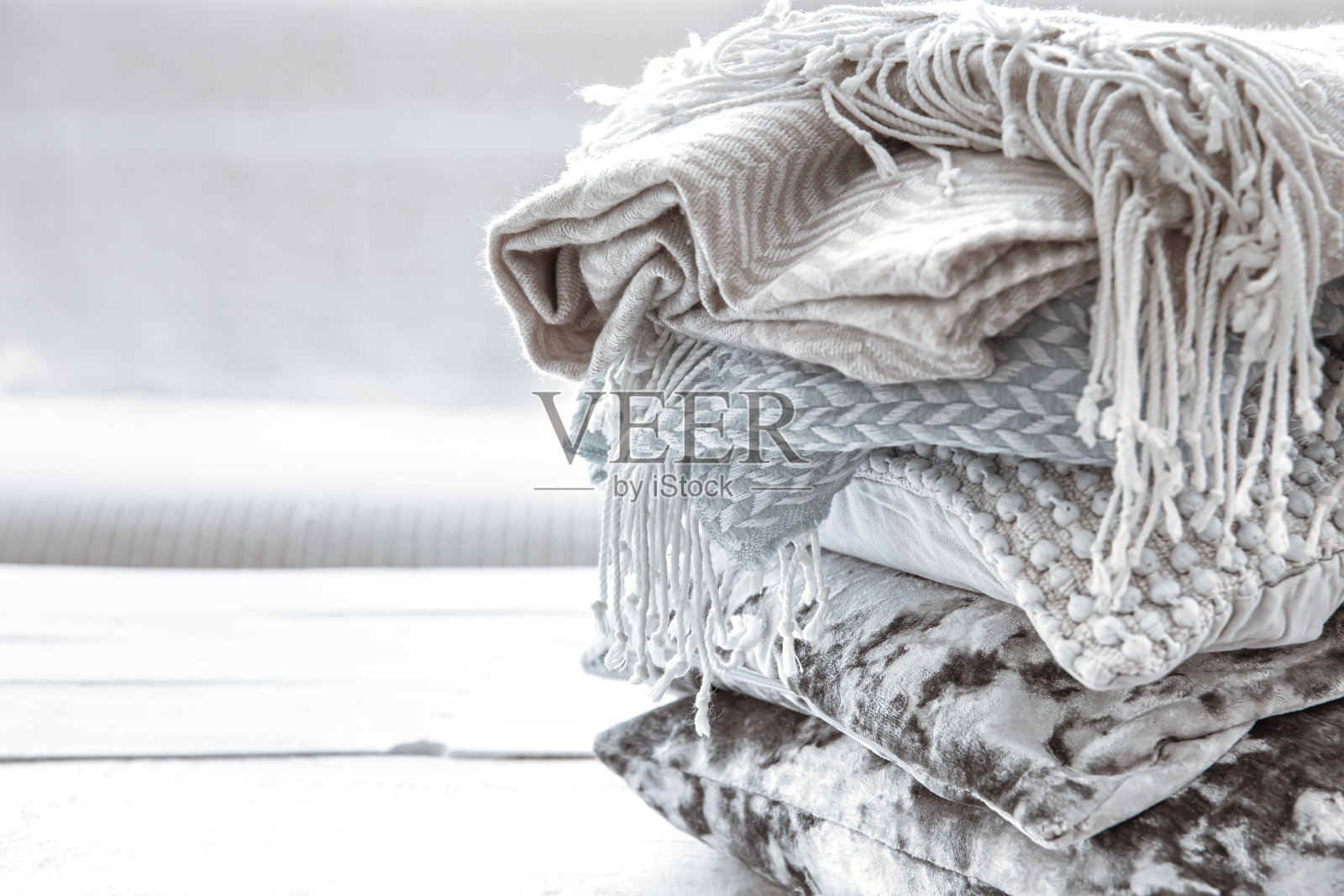 靠近一堆舒适的斯堪的纳维亚风格的毯子和枕头。照片摄影图片