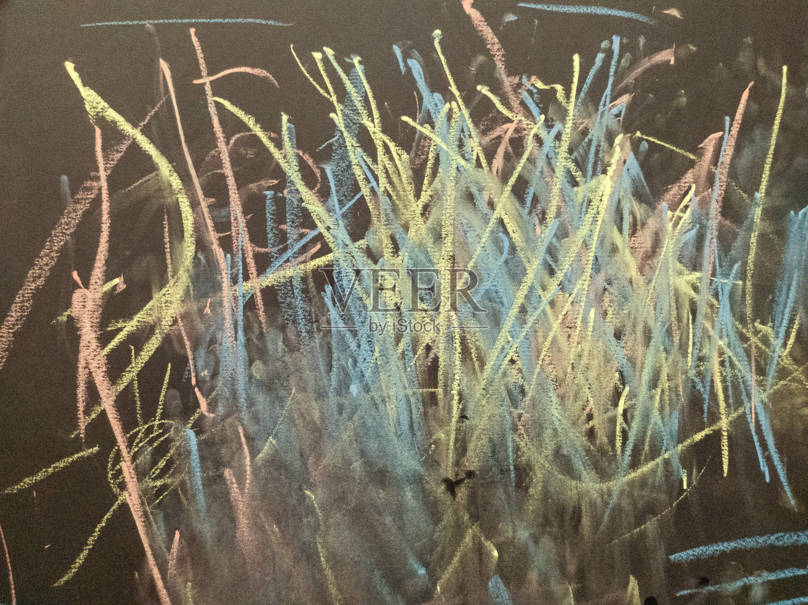 孩子们正在用粉笔在黑色的背景上画画。黄色、蓝色和粉色的粉笔。儿童绘画。抽象。背景。纹理。照片摄影图片