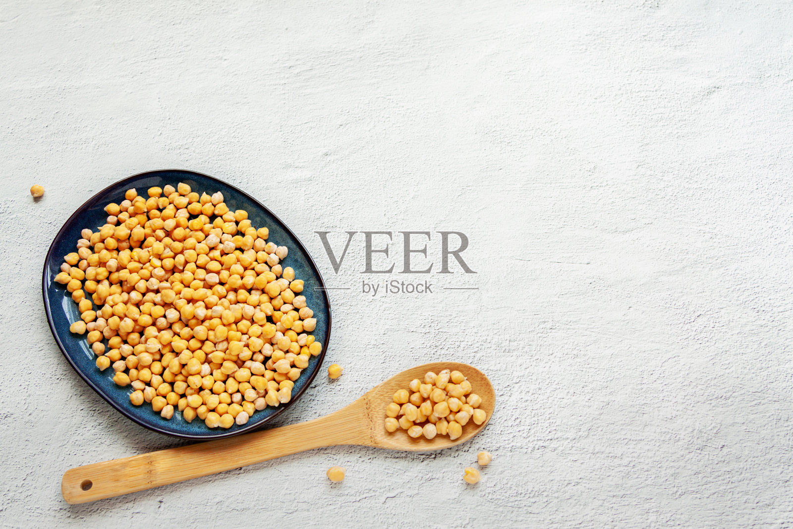 黑碗鹰嘴豆配木勺白色复制空间背景，俯视图平铺照片摄影图片