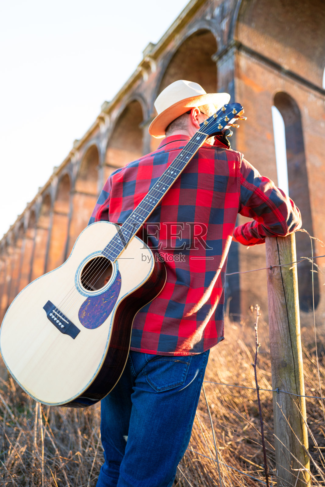 夕阳西下，一个背着吉他在大自然中游荡的人照片摄影图片