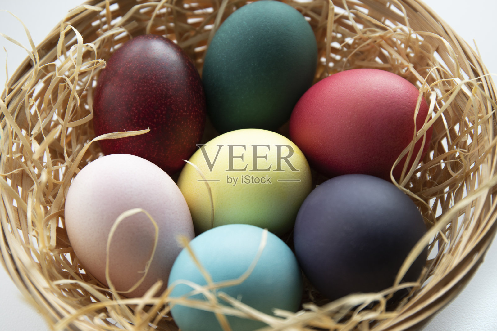 复活节彩蛋放在有稻草的柳条篮子里照片摄影图片