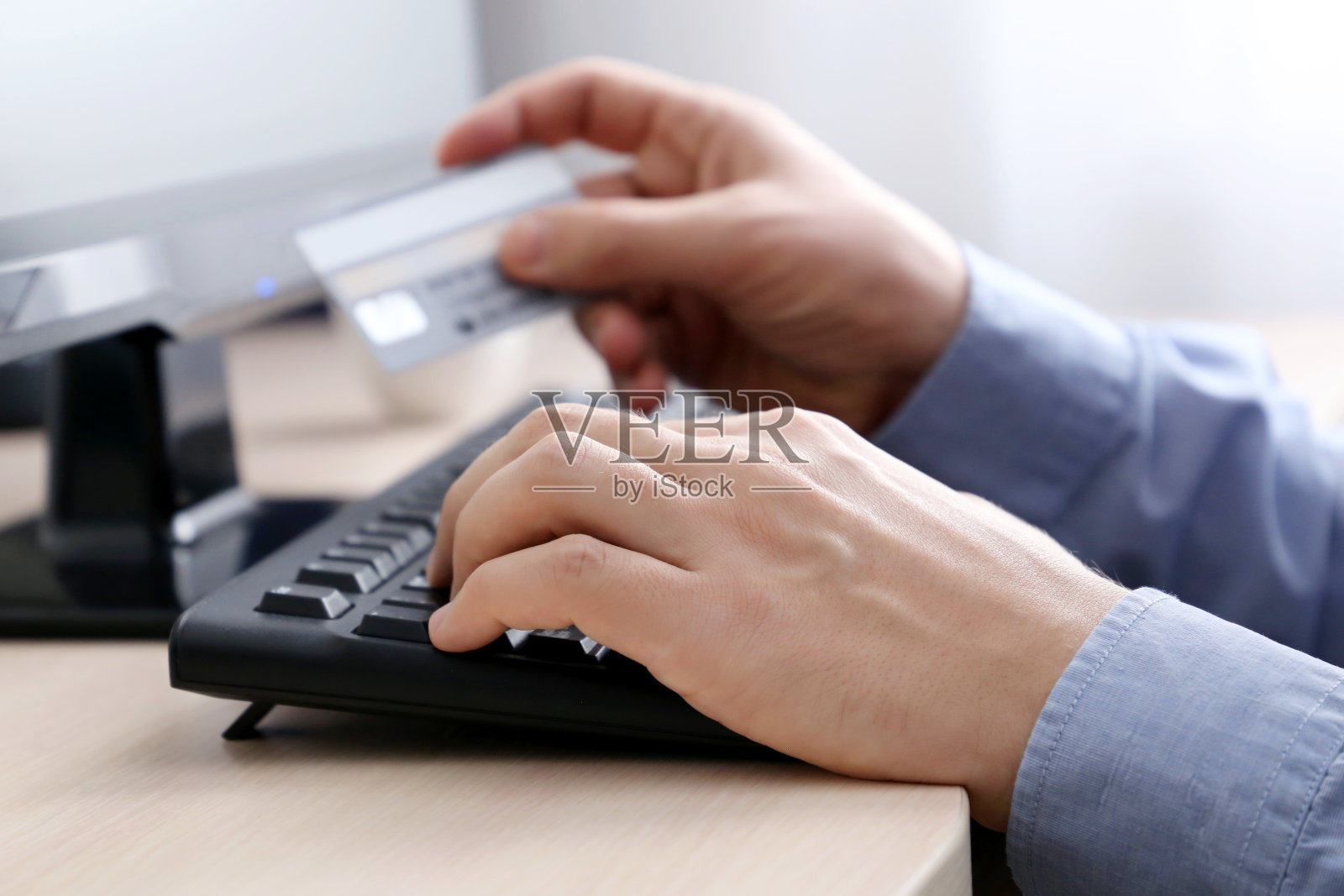 手持信用卡的男子在电脑键盘上打字照片摄影图片