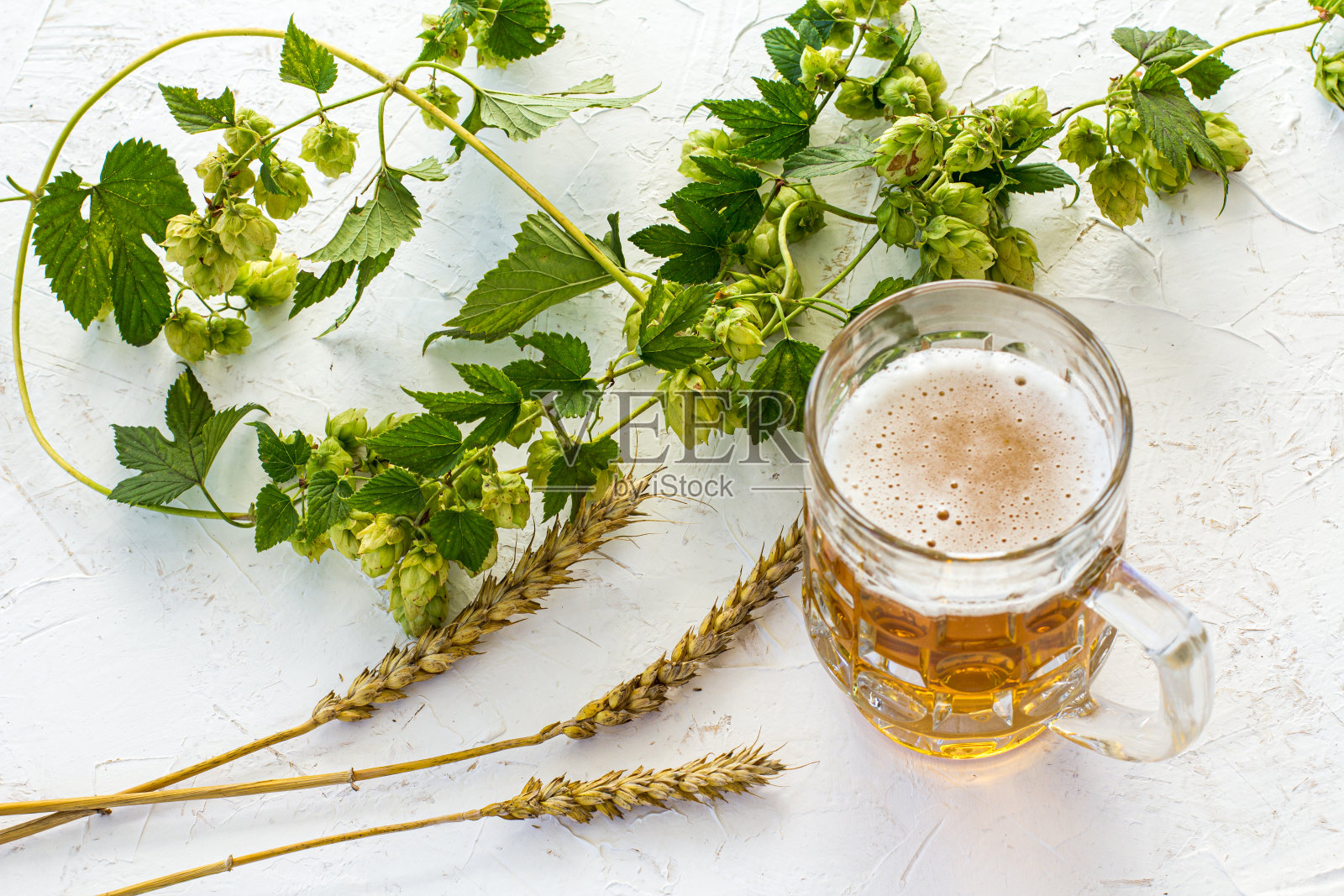 一杯啤酒和大麦穗在一个木制的背景。照片摄影图片
