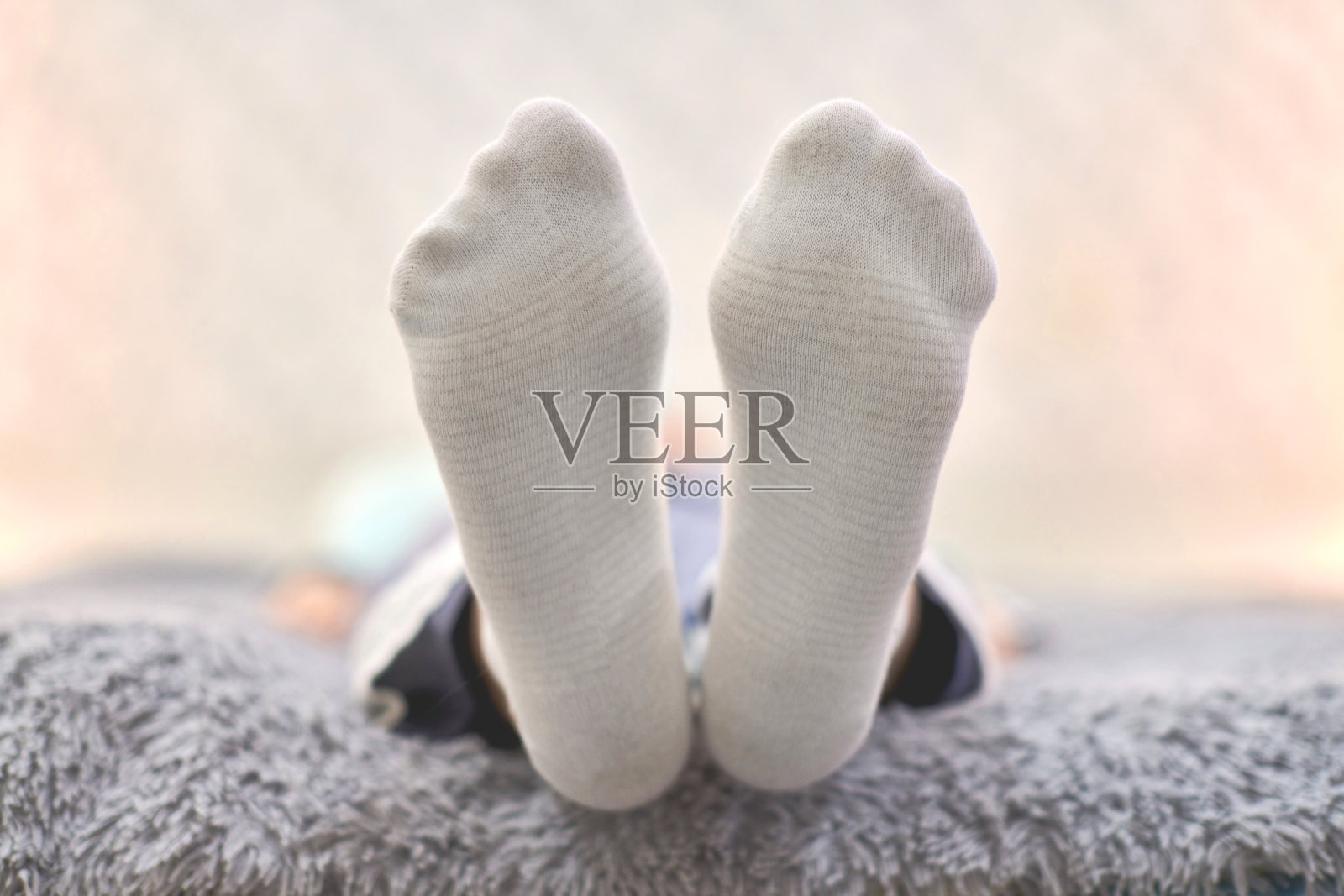 坐在沙发上穿着白色条纹袜子的女人，特写。照片摄影图片