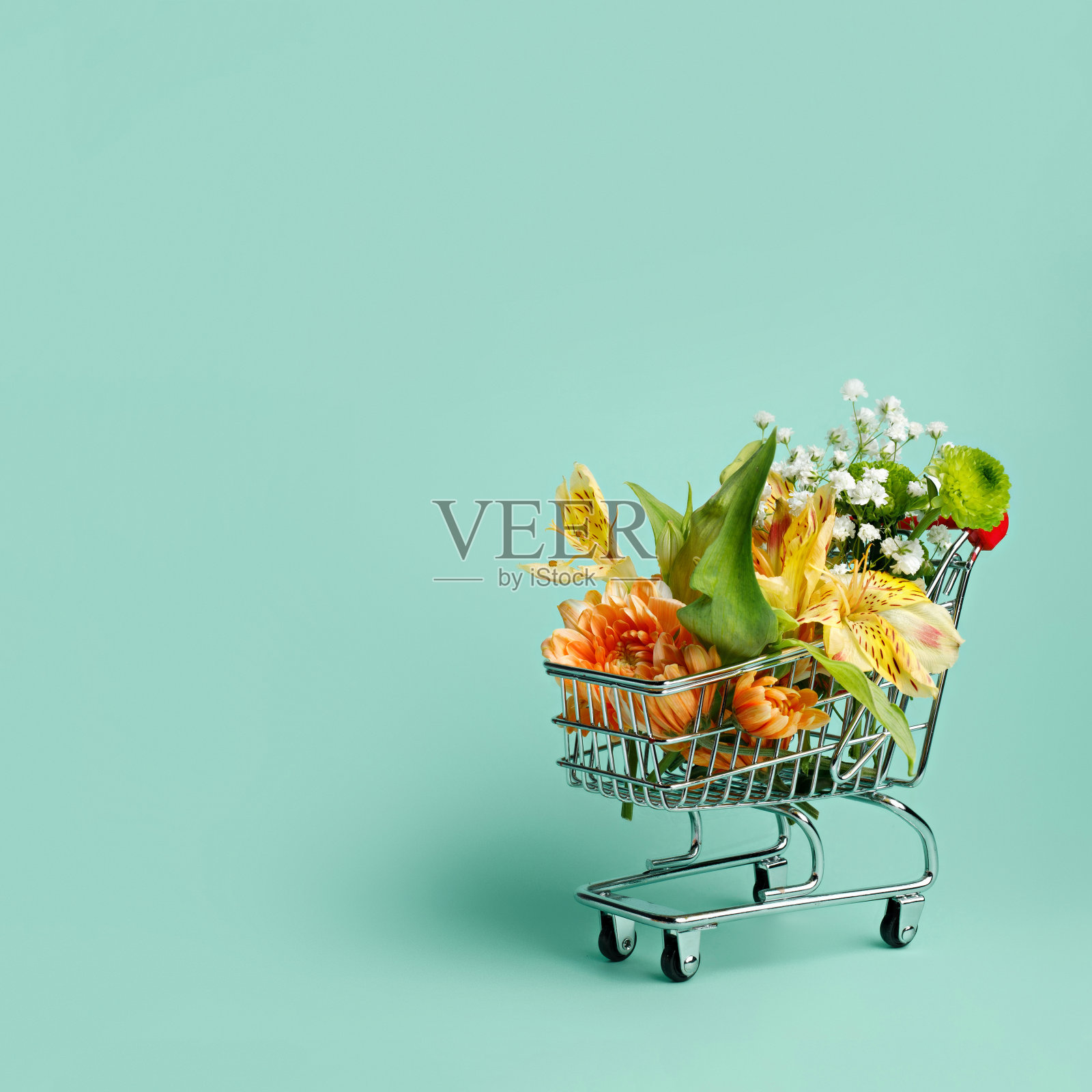 粉绿色背景的迷你购物车中的鲜花照片摄影图片