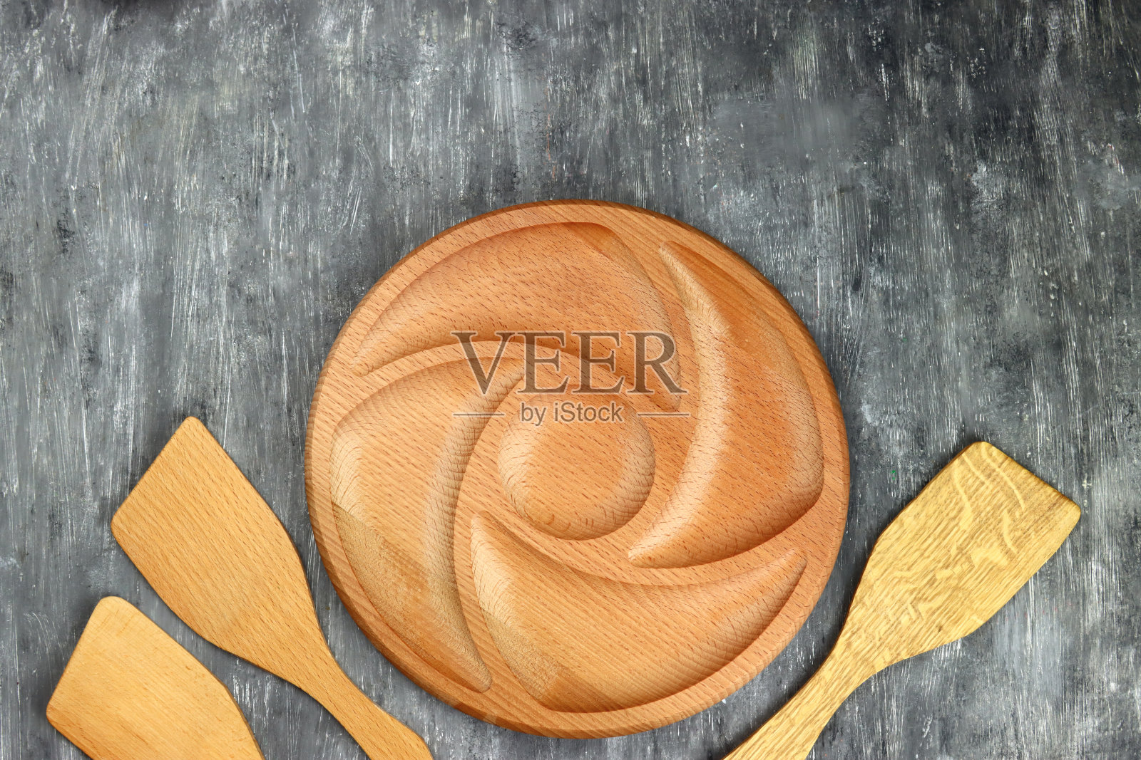 灰色背景上放着空的圆形木碟子和厨房抹刀照片摄影图片