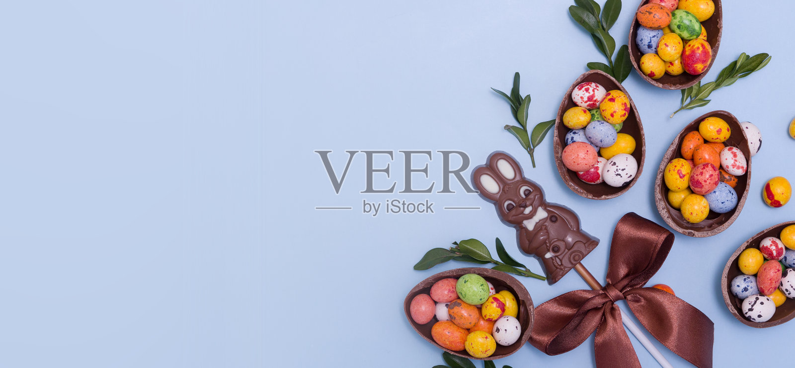 复活节旗帜蛋狩猎概念与巧克力蛋和兔子在蓝色的背景。从上面的拷贝空间查看照片摄影图片