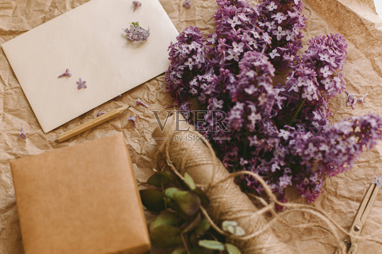 时尚的卡片，丁香花，礼物，铅笔和麻绳在乡村的背景，俯视图。农村的静物照片摄影图片