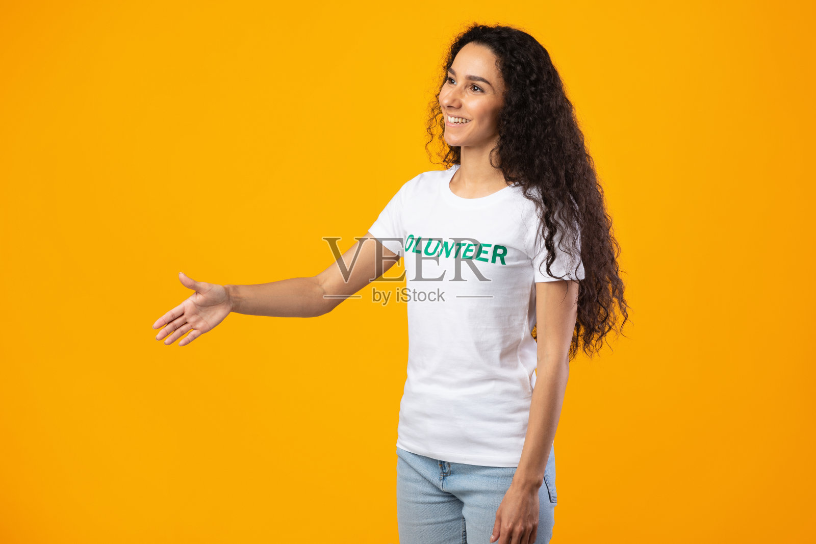侧视图的志愿者女士伸出手握手，黄色背景照片摄影图片