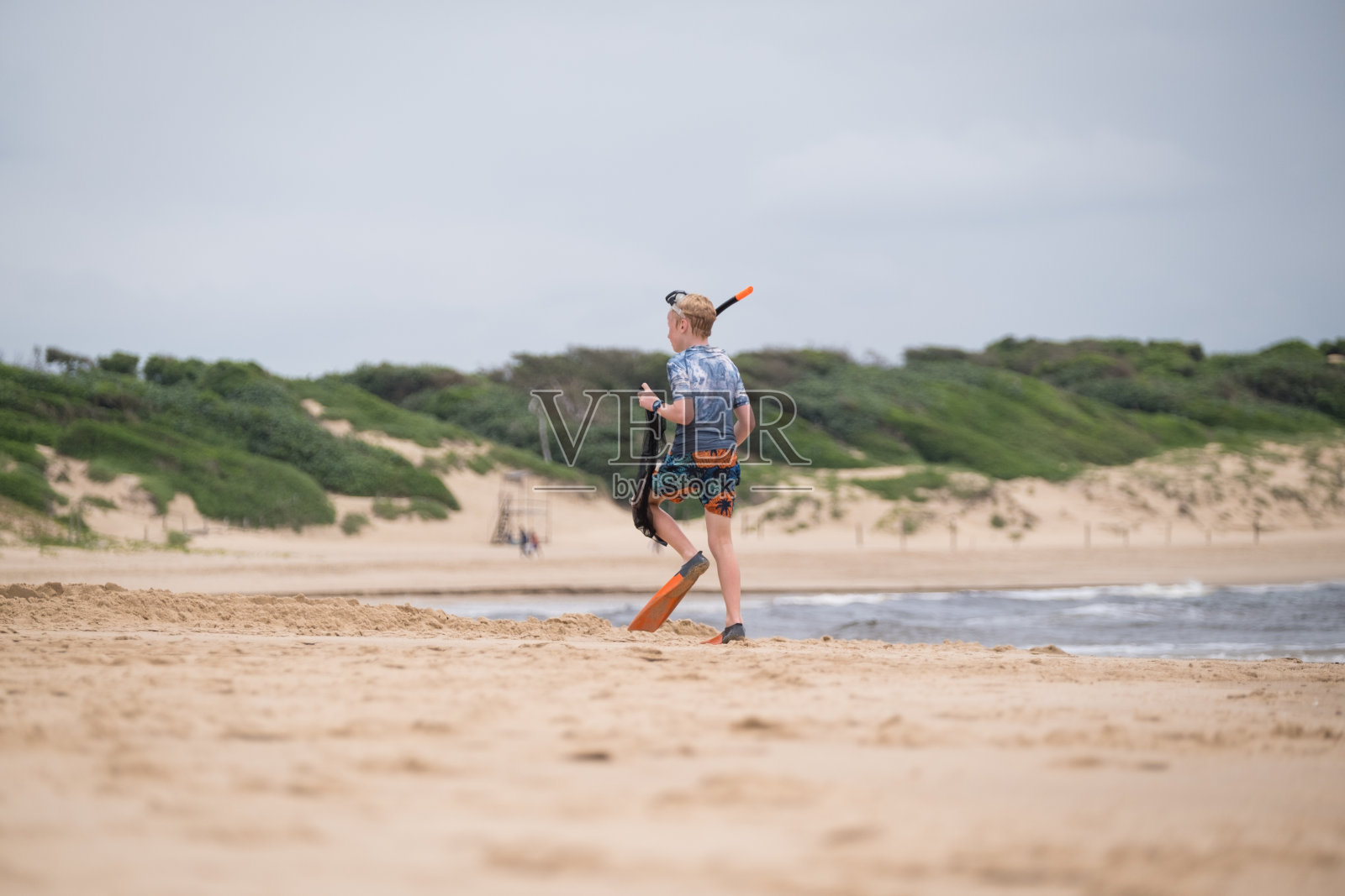 穿着潜水装备的小男孩在海滩上照片摄影图片