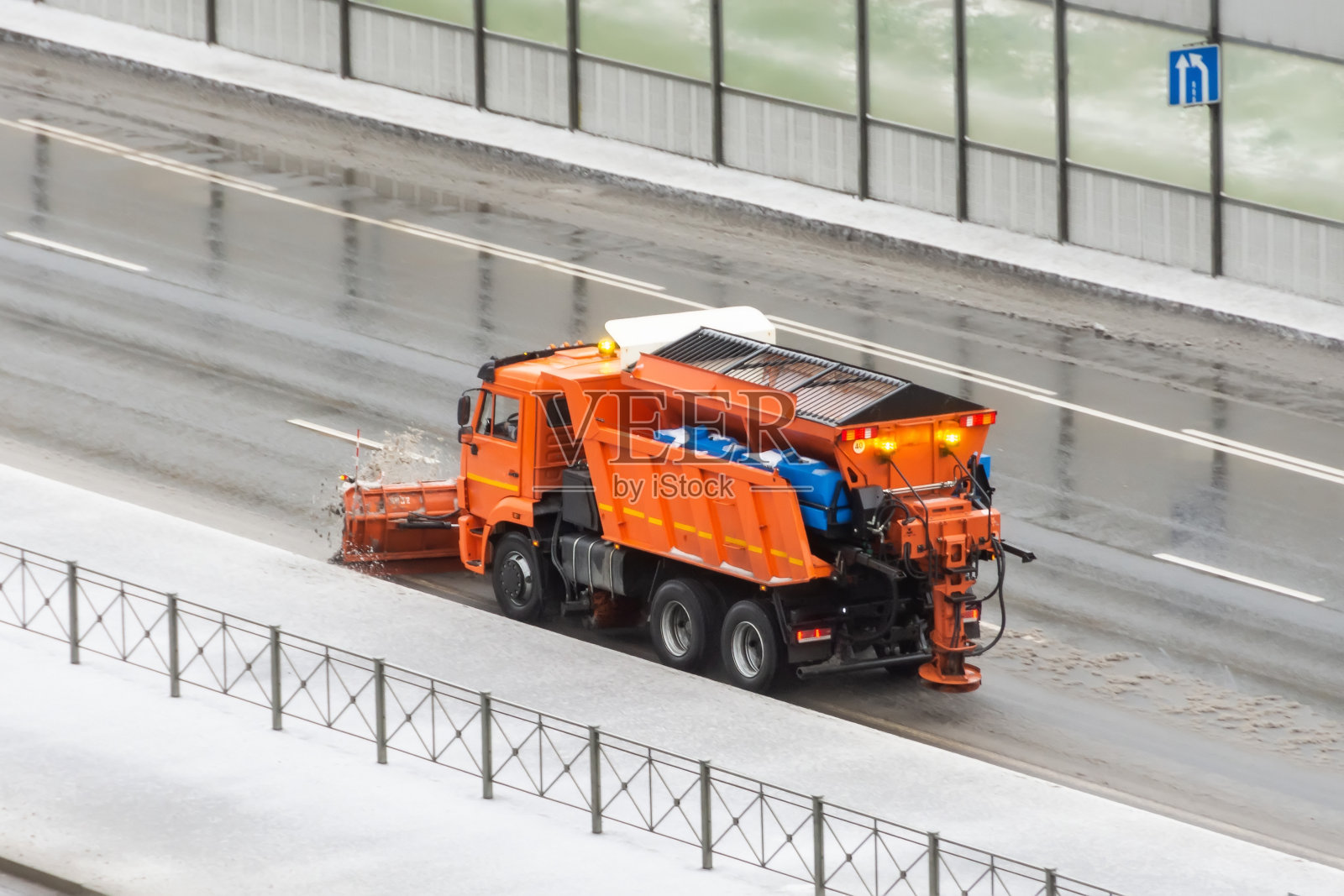 扫雪机Gritter在一条覆盖着一层薄冰的路边行驶。照片摄影图片
