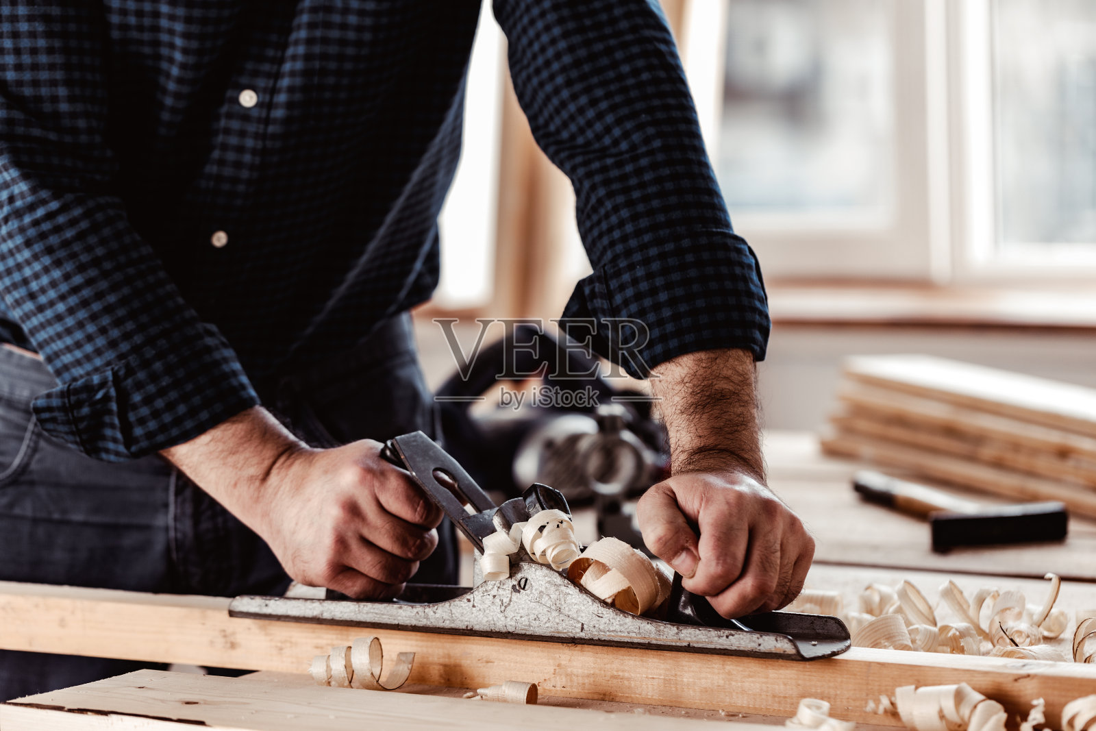 木匠的手用手刨刨一块木板照片摄影图片