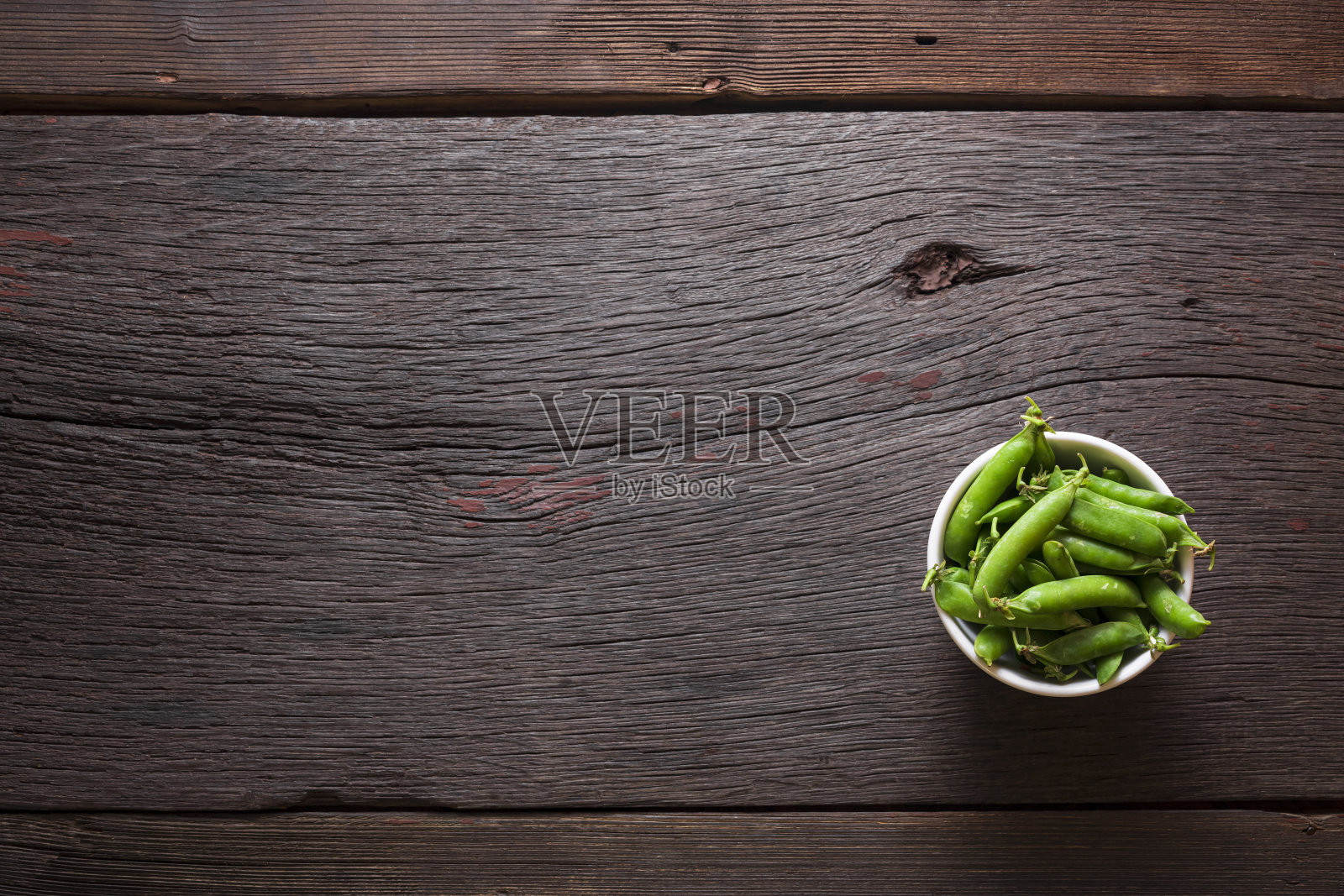 木桌上放着碗里的绿豌豆，上面有复印空间，俯视图照片摄影图片