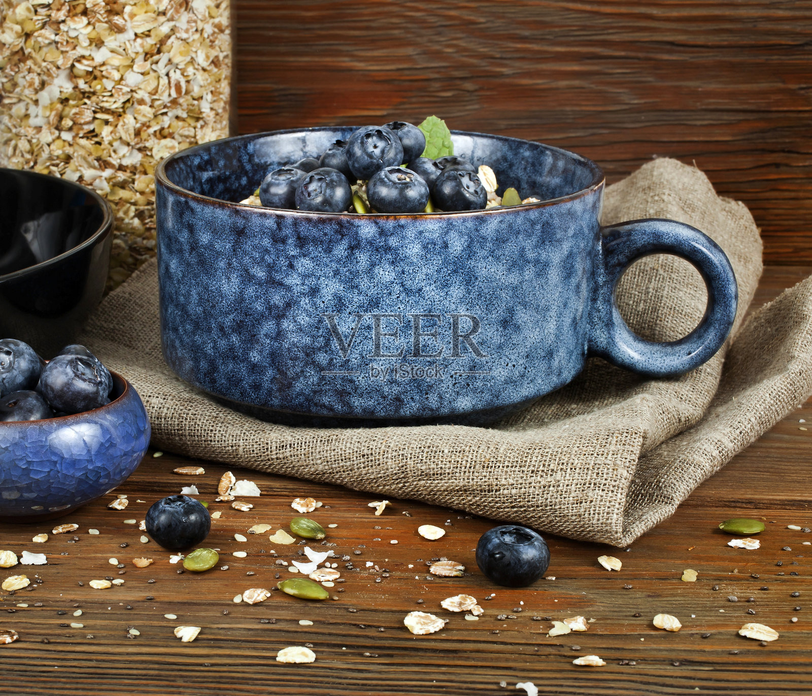 燕麦粥与蓝莓和种子在碗和燕麦片罐照片摄影图片