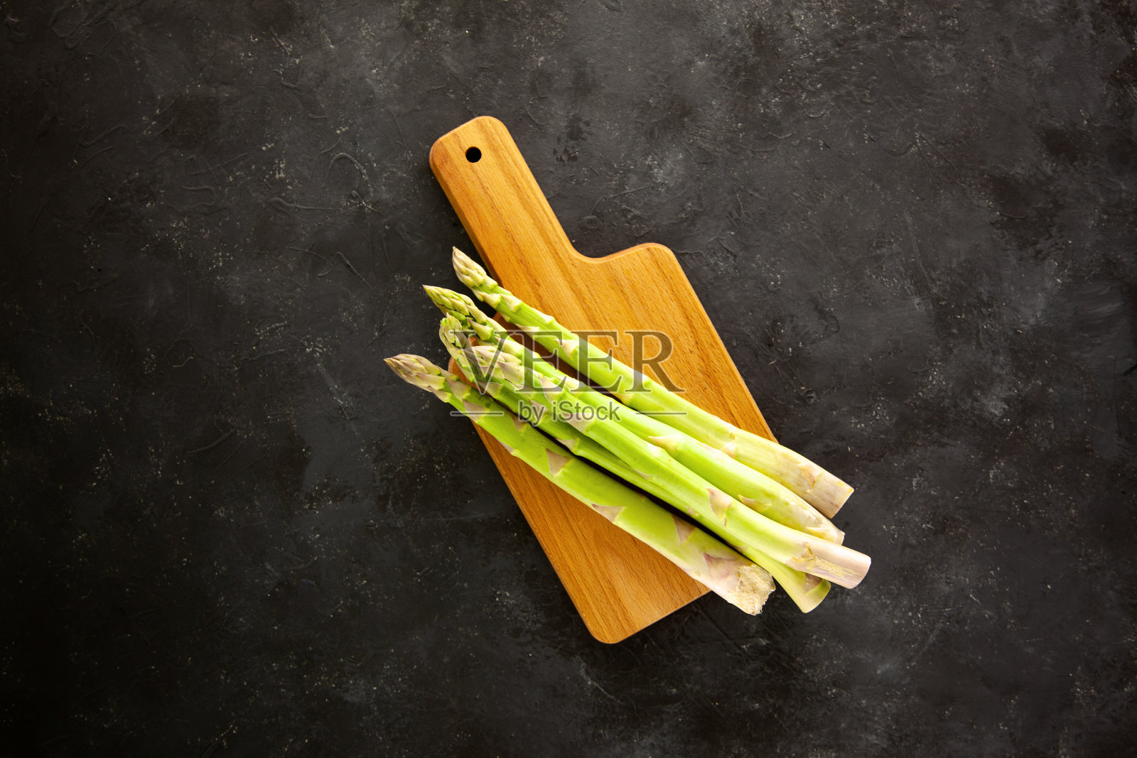 将芦笋放在木砧板上，以深灰色和白色为背景。照片摄影图片