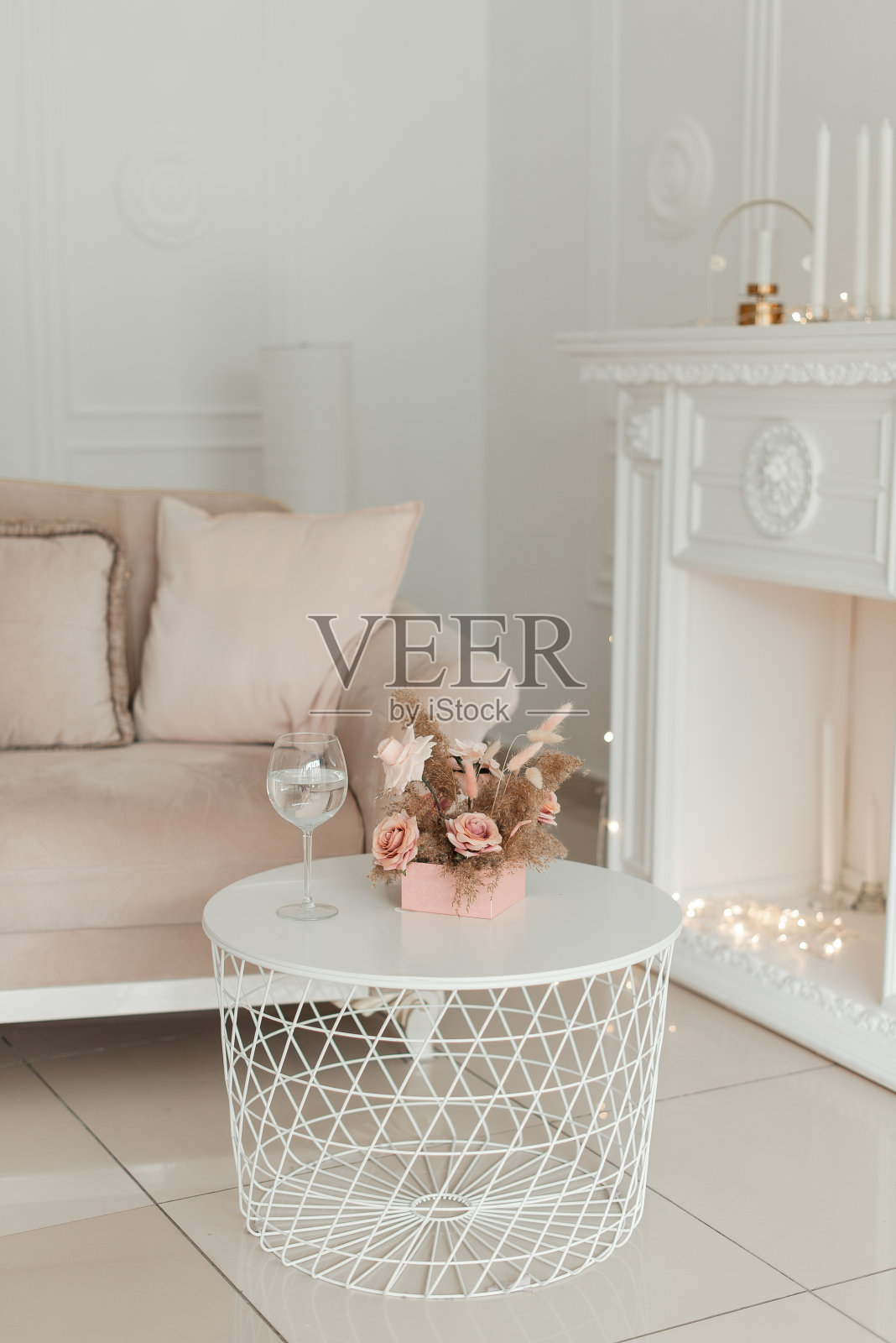 粉红色的盒子里装着人造装饰花，白色的桌子上放着一杯葡萄酒照片摄影图片