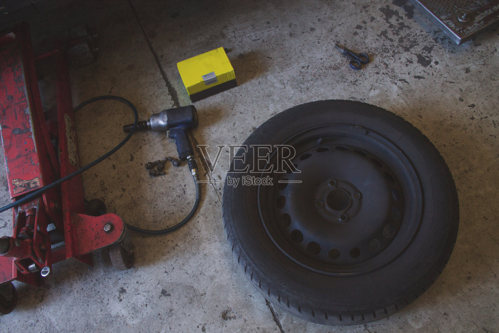 汽车机械工具(轮胎，剪刀，千斤顶，螺丝刀)与复印空间在地上。照片摄影图片