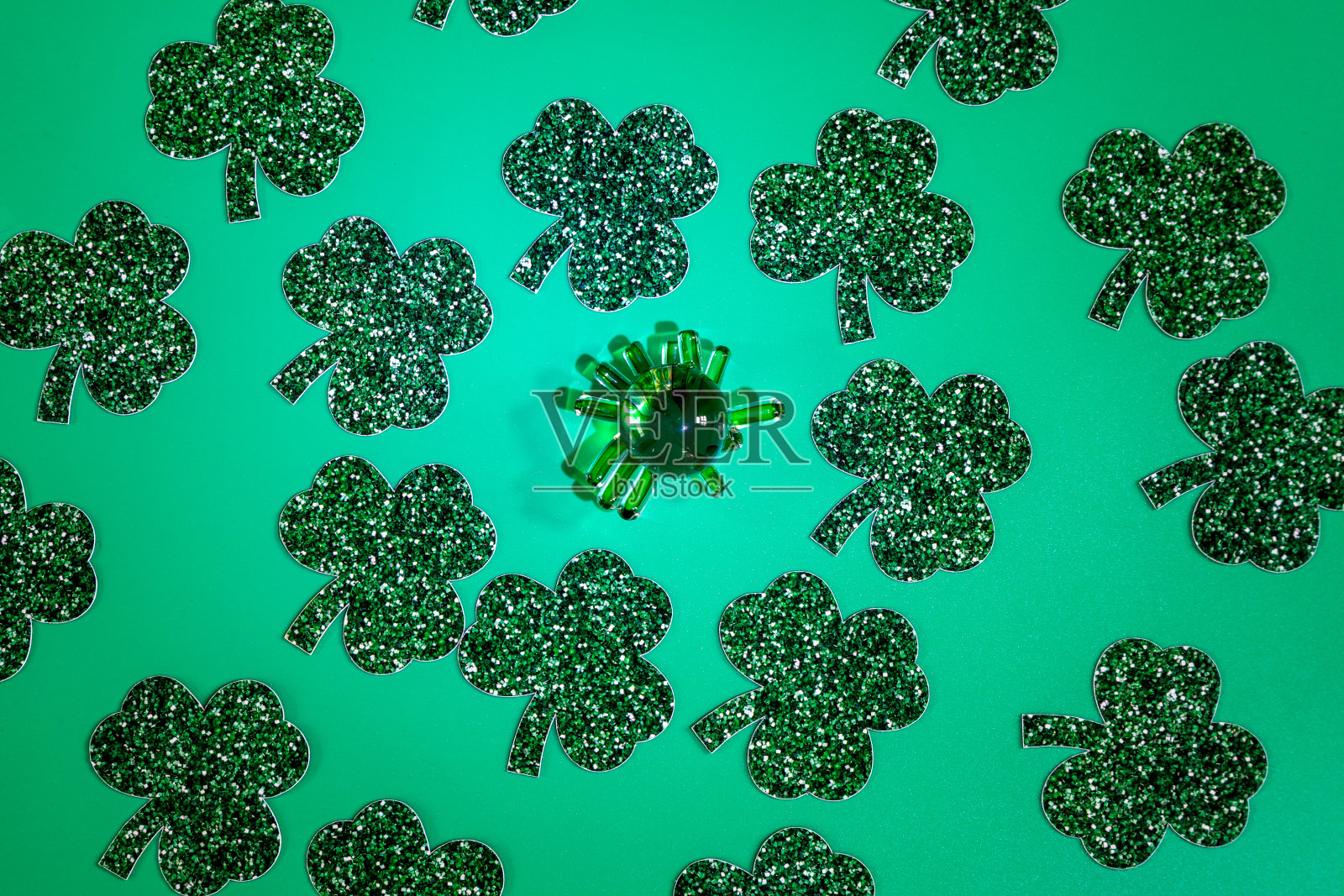 用三叶草叶子和绿色玻璃小雕像在绿色背景上的平铺构图照片摄影图片