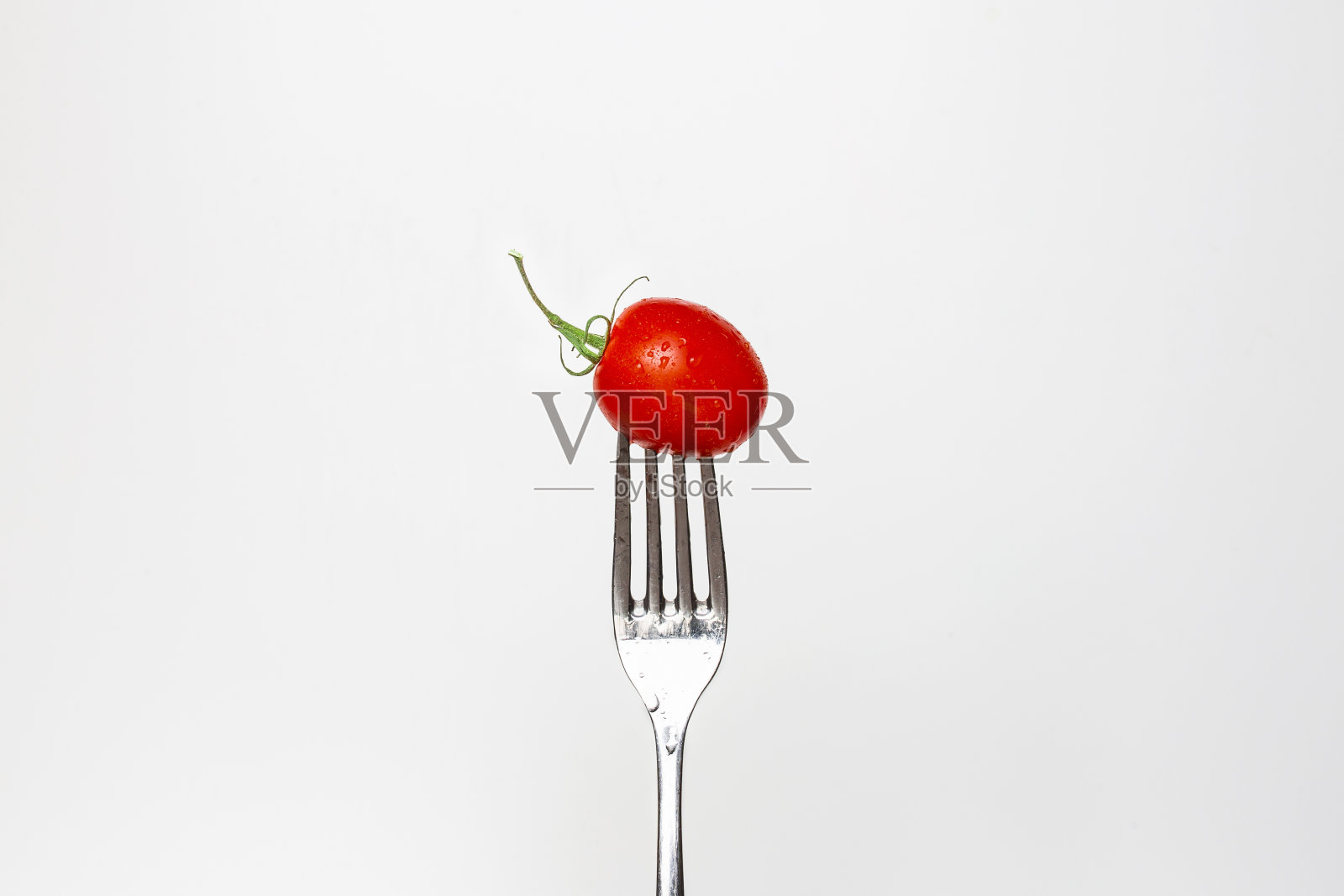 一个新鲜的樱桃番茄在叉子孤立的白色背景的照片，系列的一部分。照片摄影图片