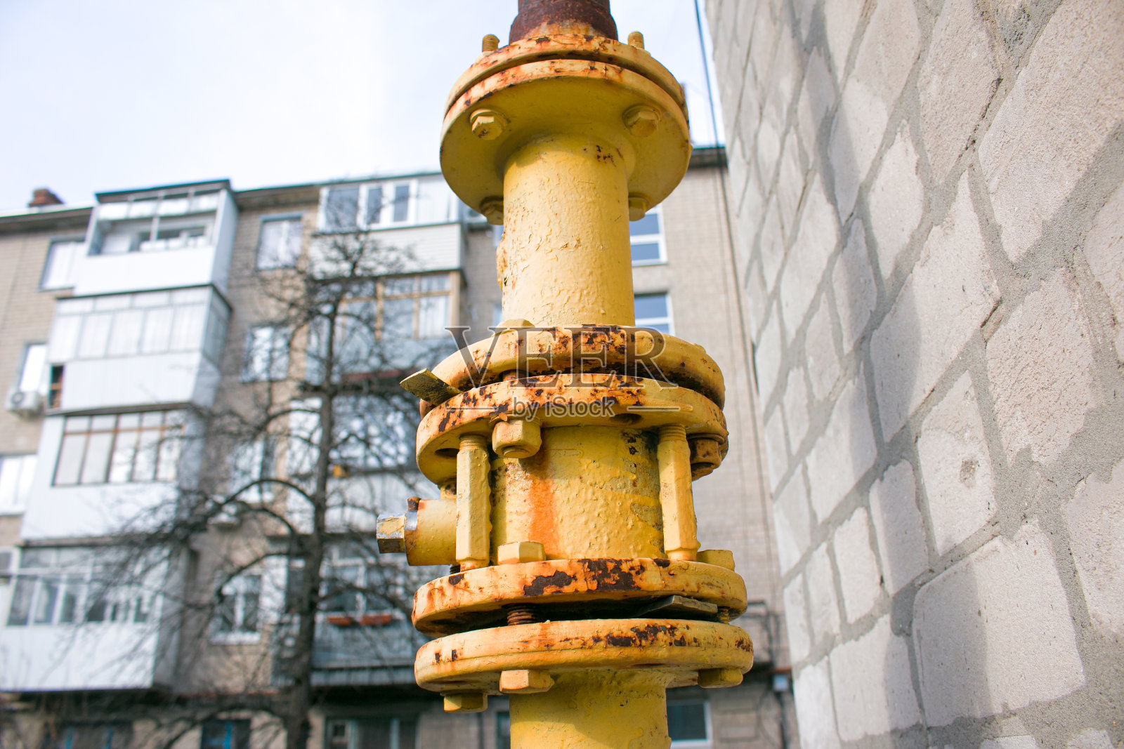 黄色的带阀门启闭的煤气管道沿多层建筑立面布置。连接煤气供家庭使用的房屋。照片摄影图片