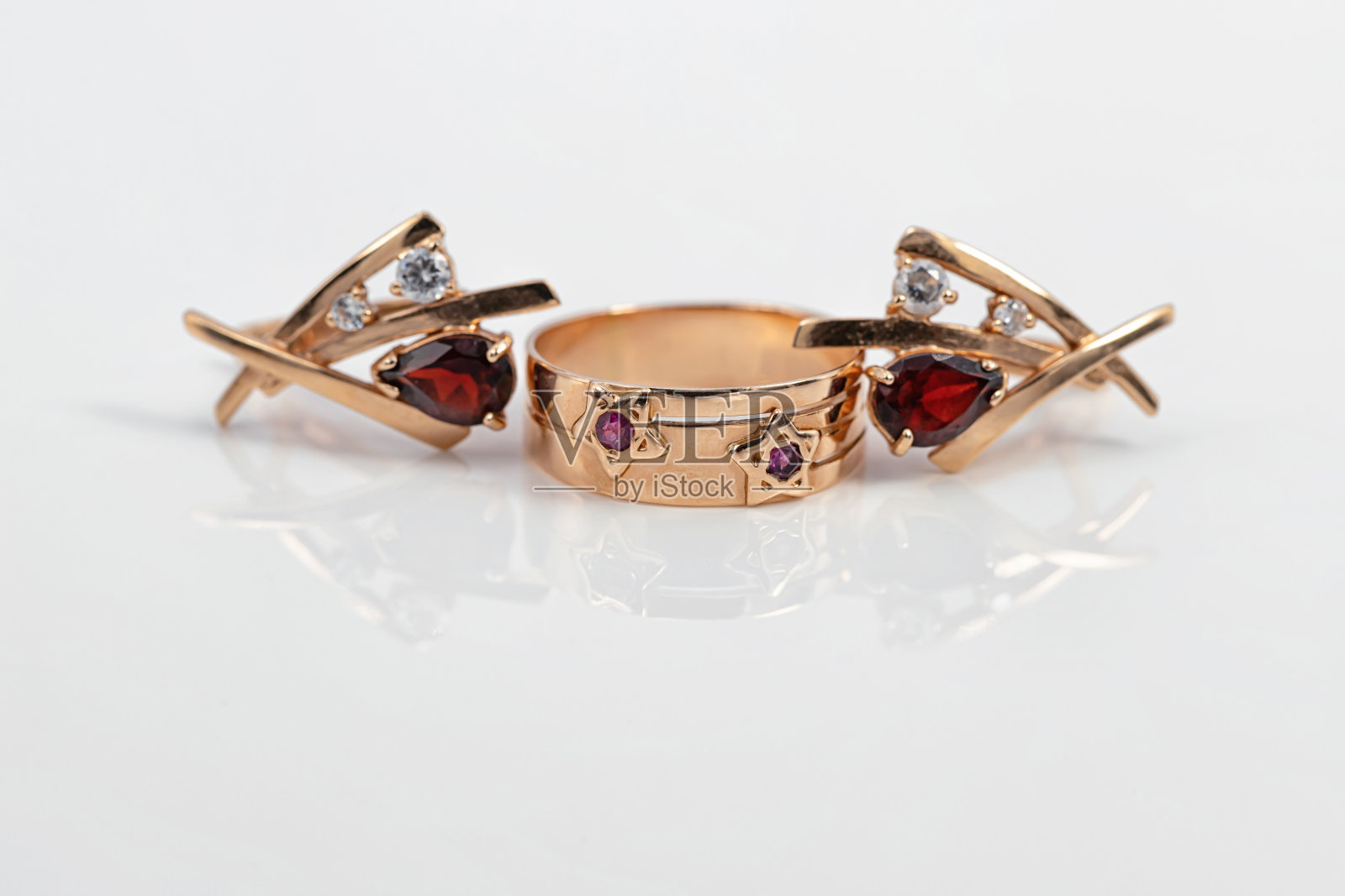 镶有红宝石的星状金戒指和红宝石耳环照片摄影图片