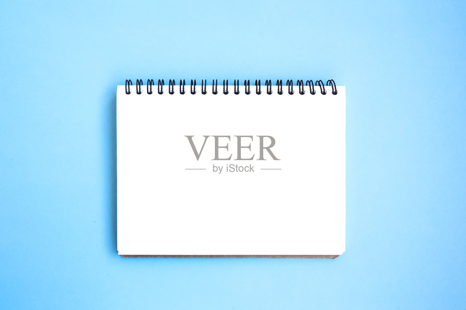 打开白色的记事本，上面有亮蓝色背景上螺旋形的题词照片摄影图片