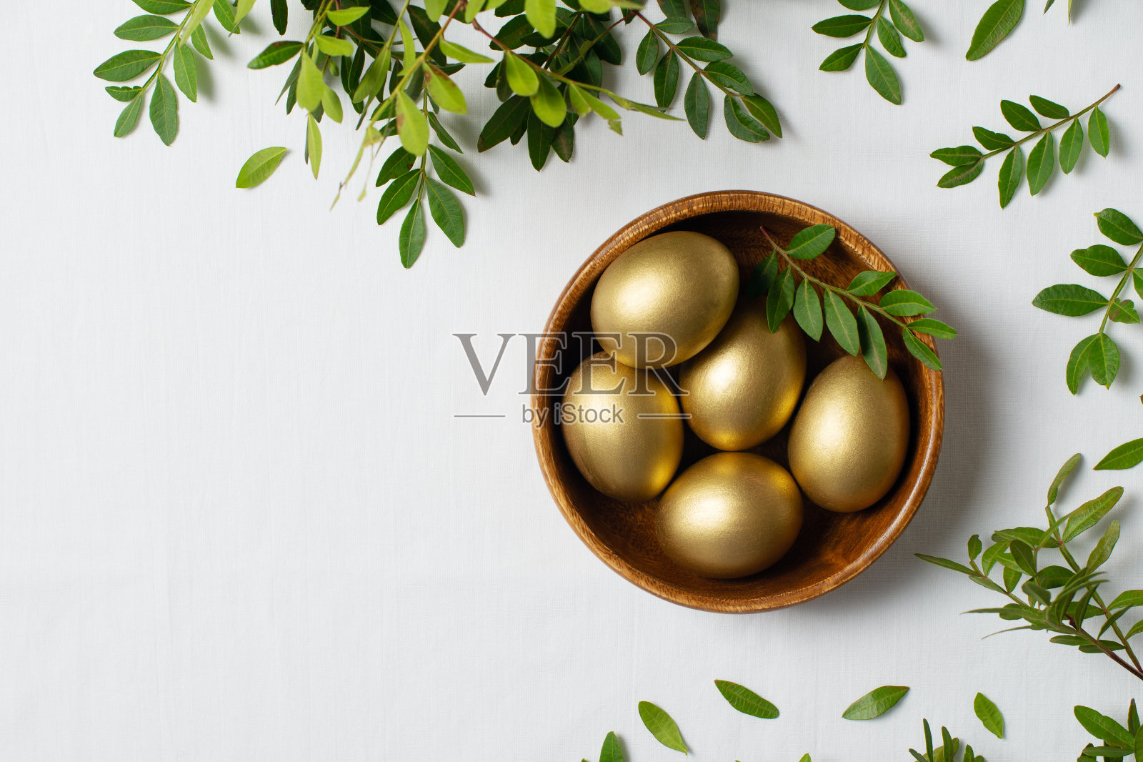 复活节概念与金蛋和树枝与绿叶在白色的背景照片摄影图片