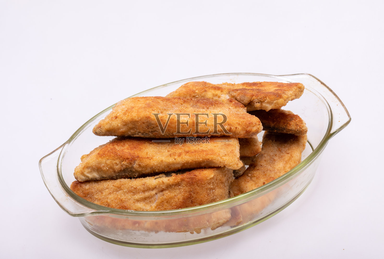 裹有面包屑的鱼片，盛在耐热玻璃器皿中照片摄影图片