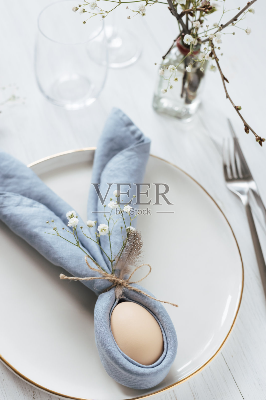 复活节餐桌与鸡蛋在蓝色复活节兔子餐巾。照片摄影图片