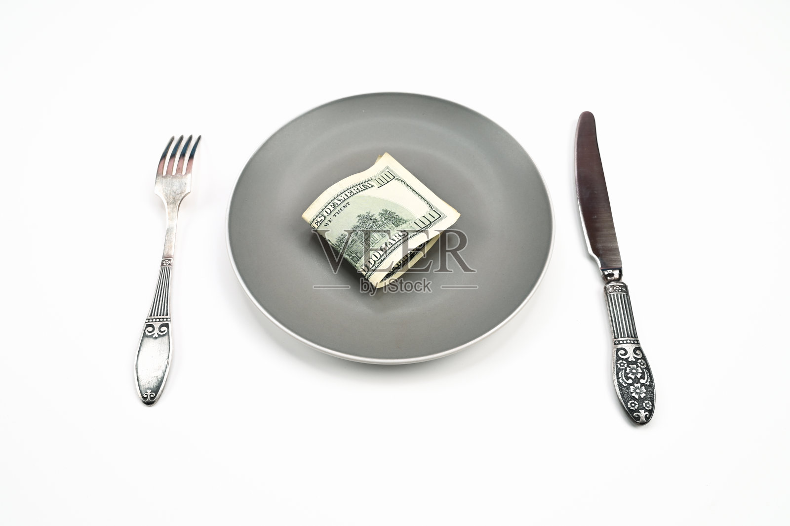 百元大钞放在盘子里，叉子和刀放在孤立的白色背景上照片摄影图片