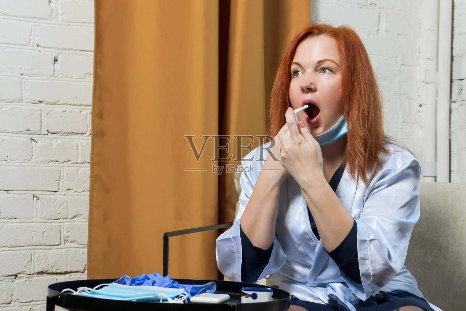 年轻的红头发女人正在治疗咽喉喷雾剂。概念:治疗感冒初征照片摄影图片