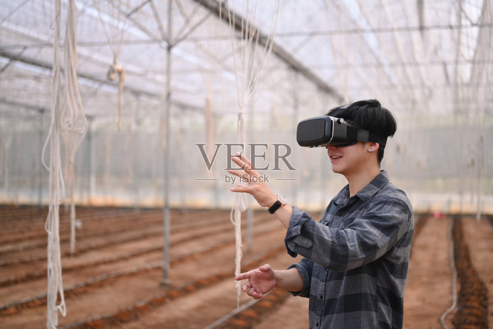 年轻的亚洲人聪明的农民站在温室和戴视觉现实眼镜技术。照片摄影图片