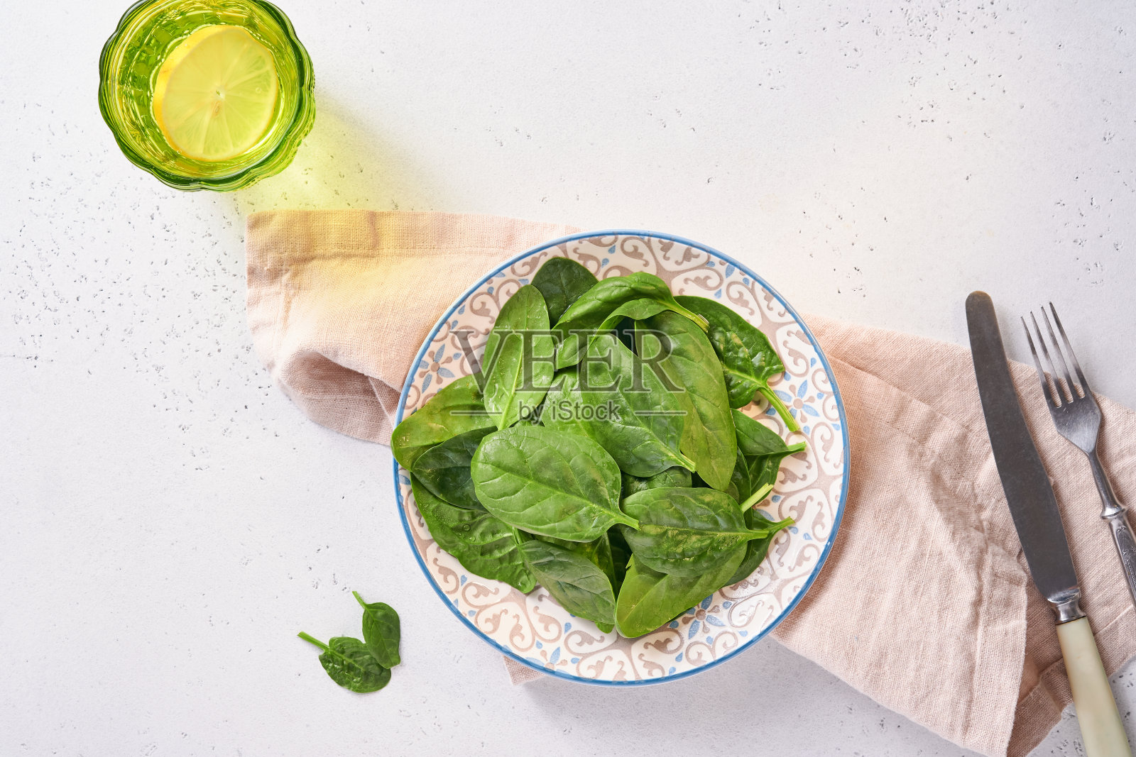 新鲜菠菜叶在陶瓷漂亮的碗，浅灰色的混凝土背景。模拟。俯视图照片摄影图片