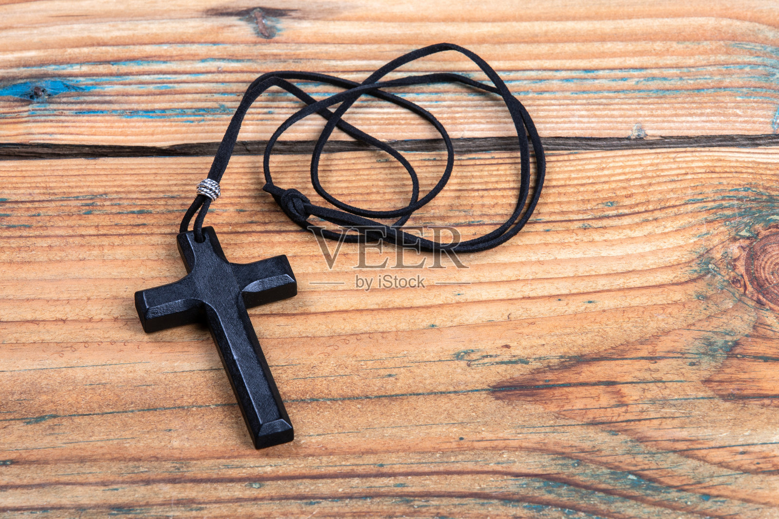 十字与皮革绳在木质纹理的背景照片摄影图片