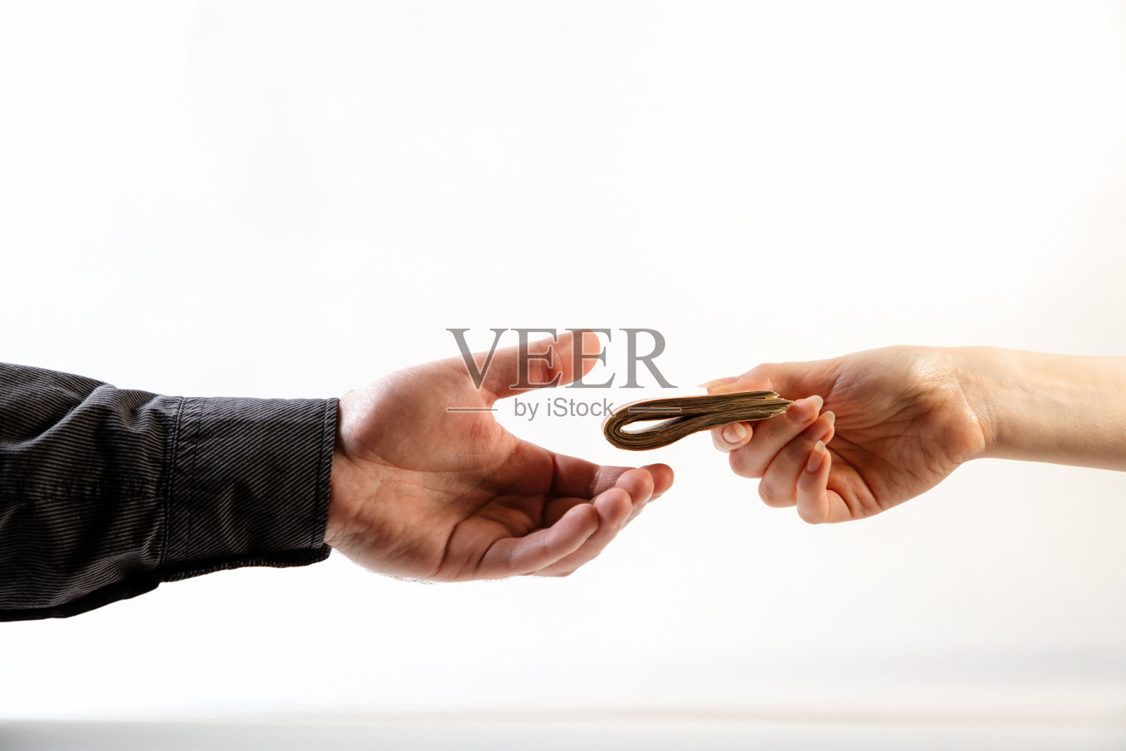 一个穿着黑衬衫的男人从一个女人的手里接过一叠叠好的钱。侧视图。白色背景。世界反腐败日的概念，12月9日照片摄影图片