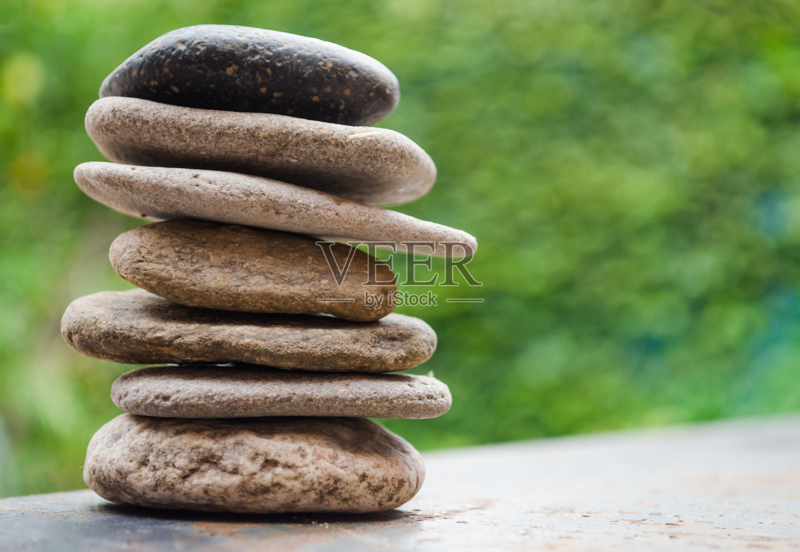 在模糊的背景上堆叠平滑的灰色石头。海卵石在自然界中堆积。平衡与和谐理念。照片摄影图片