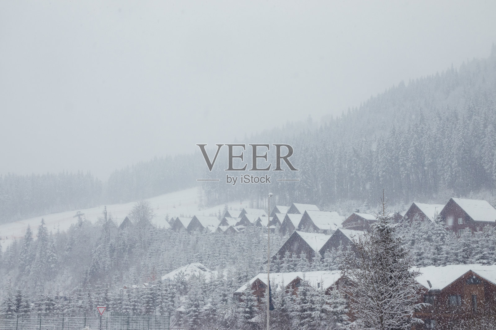 山里的一场暴风雪席卷了木屋。雪中的木屋和圣诞树。喀尔巴阡山。乌克兰照片摄影图片