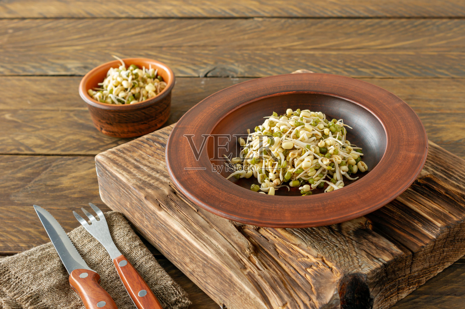 发芽的食物。在质朴的木制背景下，盘子里放着发芽的豆子。长寿法照片摄影图片