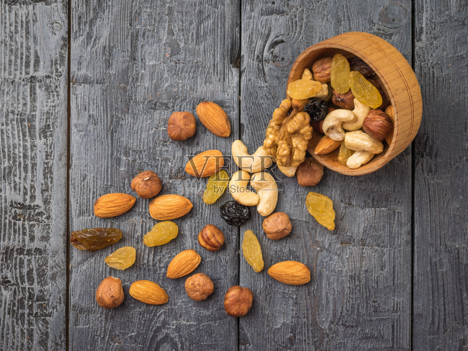 木桌上放着一个木碗，上面撒着坚果和干果。照片摄影图片