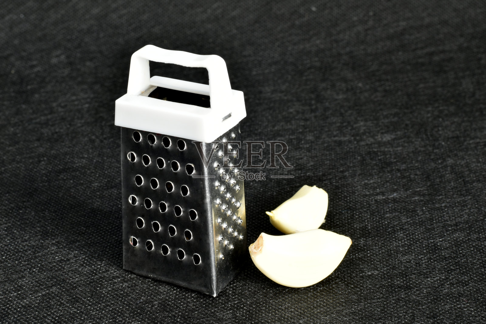 小金属磨碎器和蒜瓣。照片摄影图片