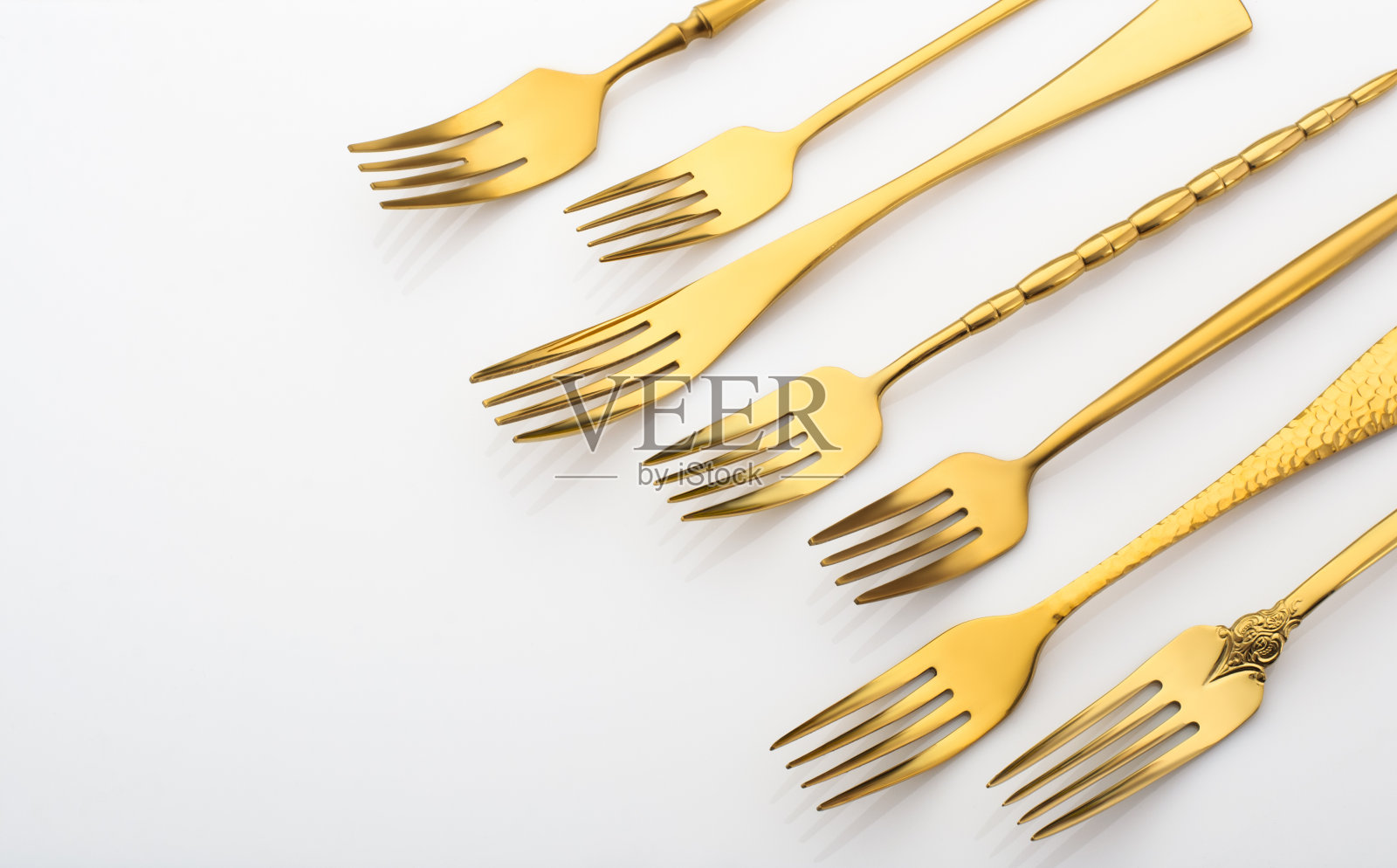 许多金色的叉子在白色的背景，金色的餐具照片摄影图片