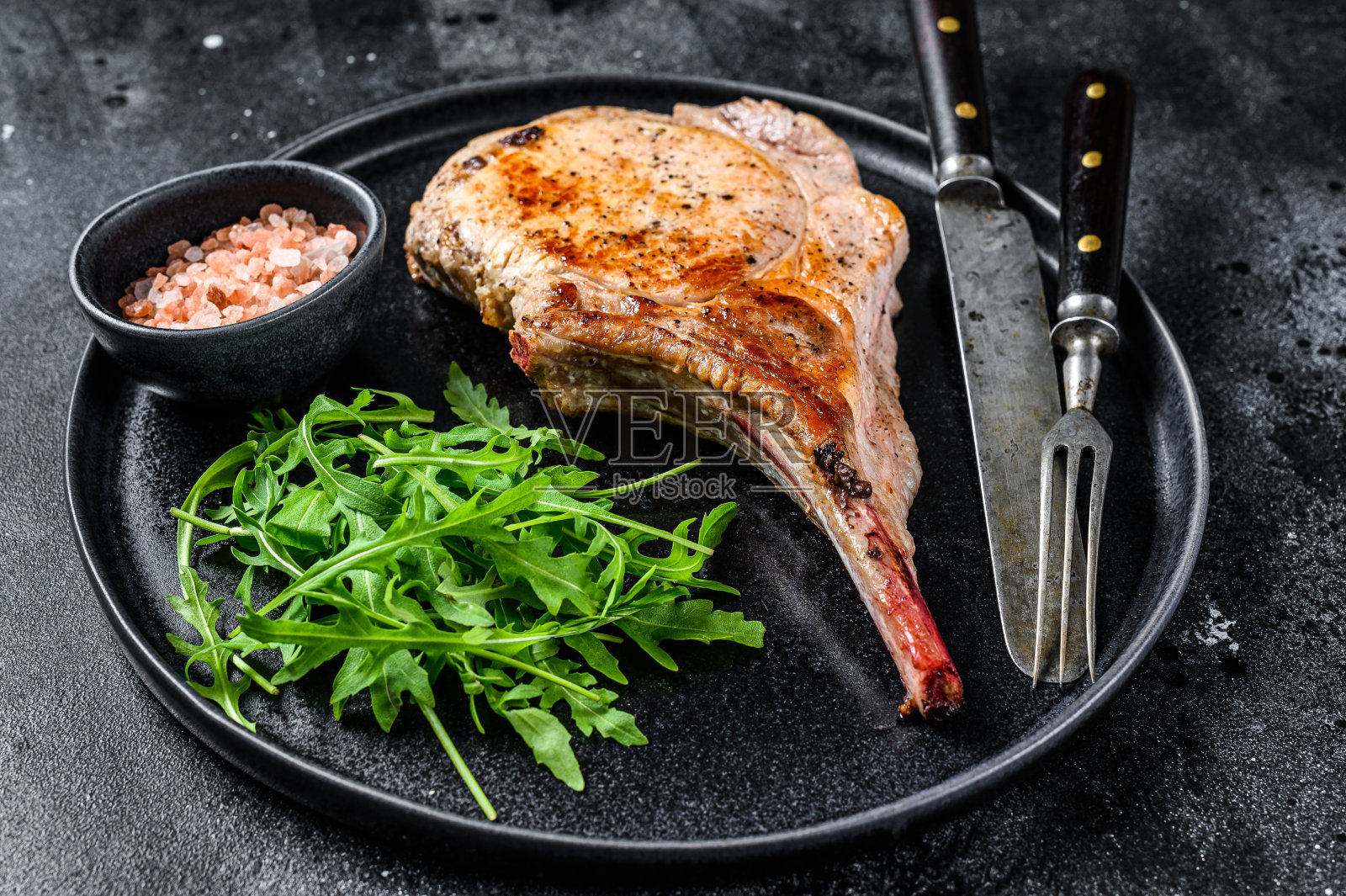 烤炙战斧猪肉切肉排在大理石板上。黑色背景。俯视图照片摄影图片