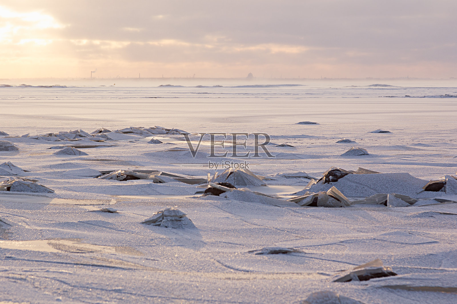 柔和的光金色的日落在冬天结冰的海岸与破碎的冰，水平，阳光和闪亮的雪，风景在柔和的粉红色和蓝色。照片摄影图片