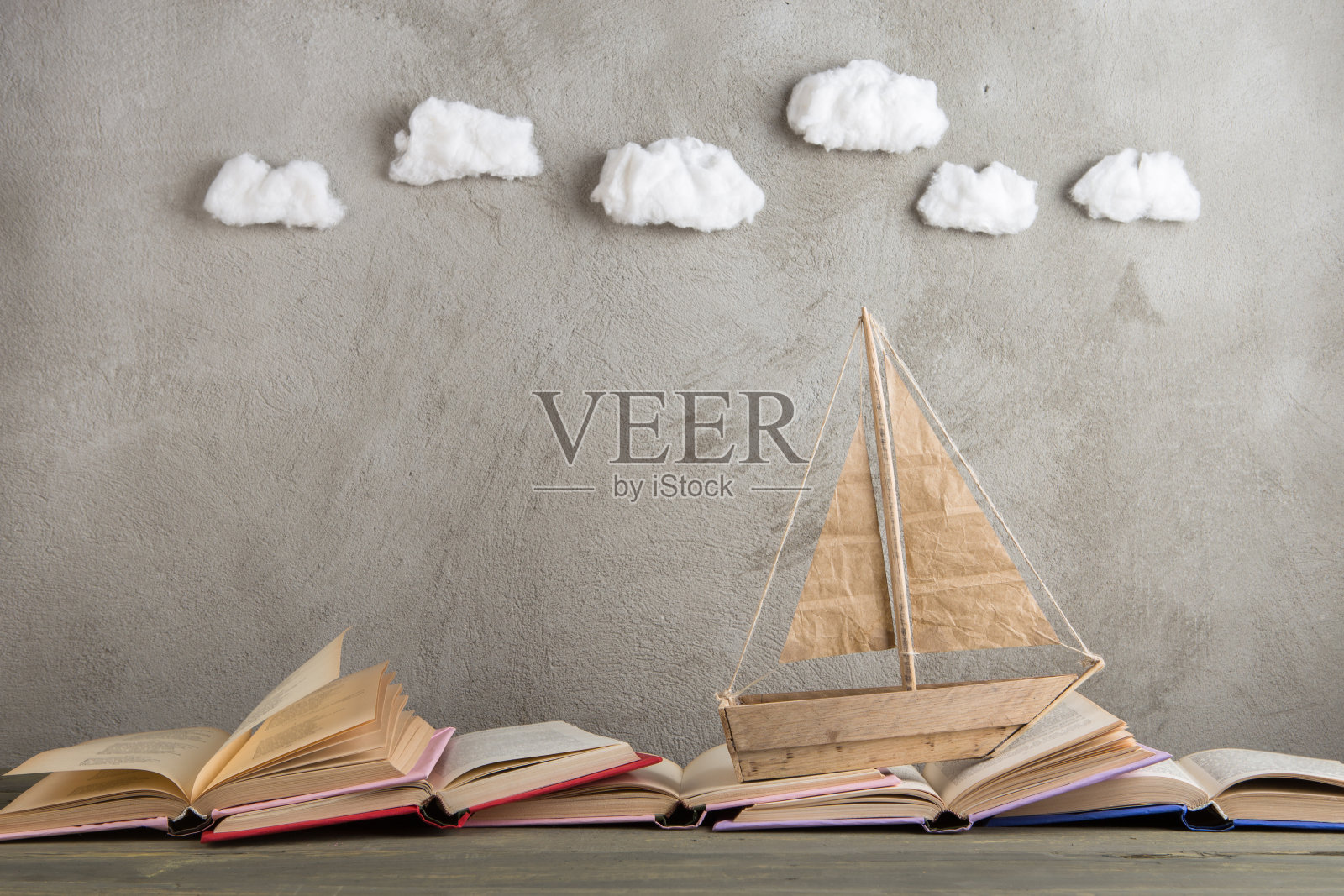 教育是一种旅行的概念，玩具船和书像海浪一样放在木桌上，启发着一个写童话的人照片摄影图片