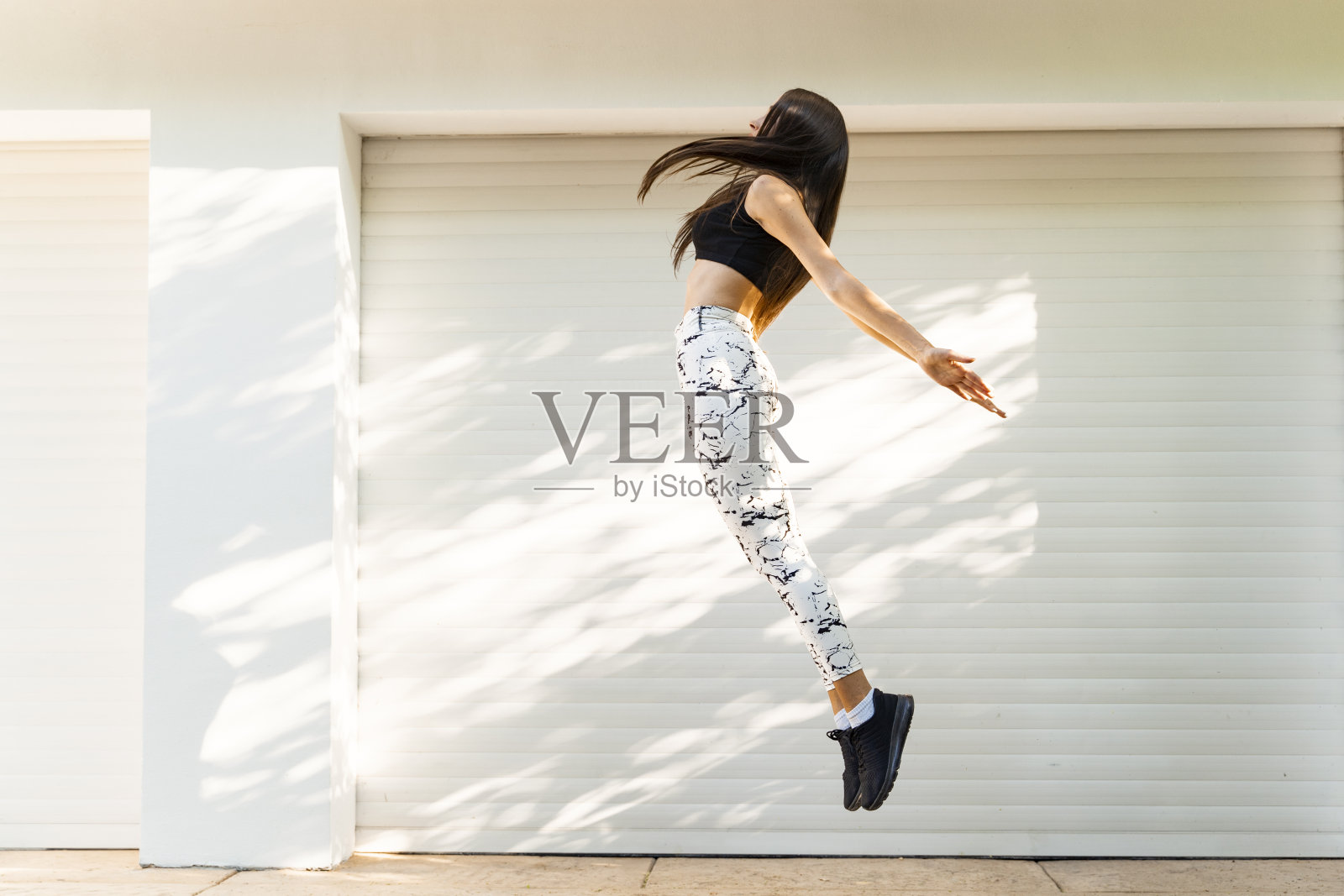 年轻女子穿着运动服，精力充沛，在空中蹦蹦跳跳照片摄影图片